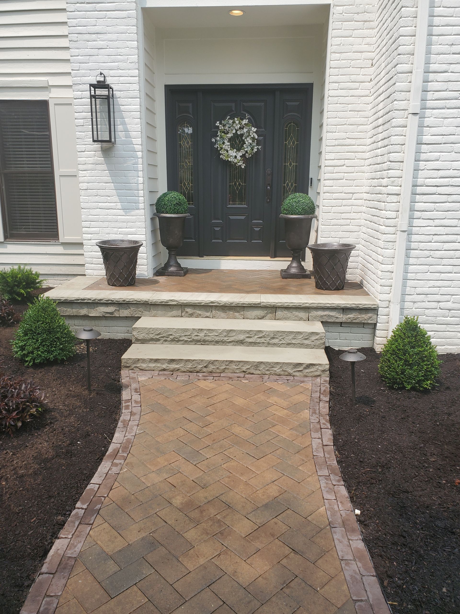 A brick walkway leading to the front door of a house.