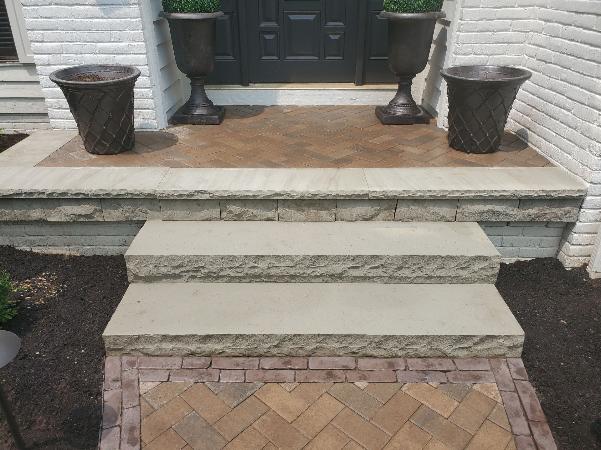 A front porch with stairs and potted plants