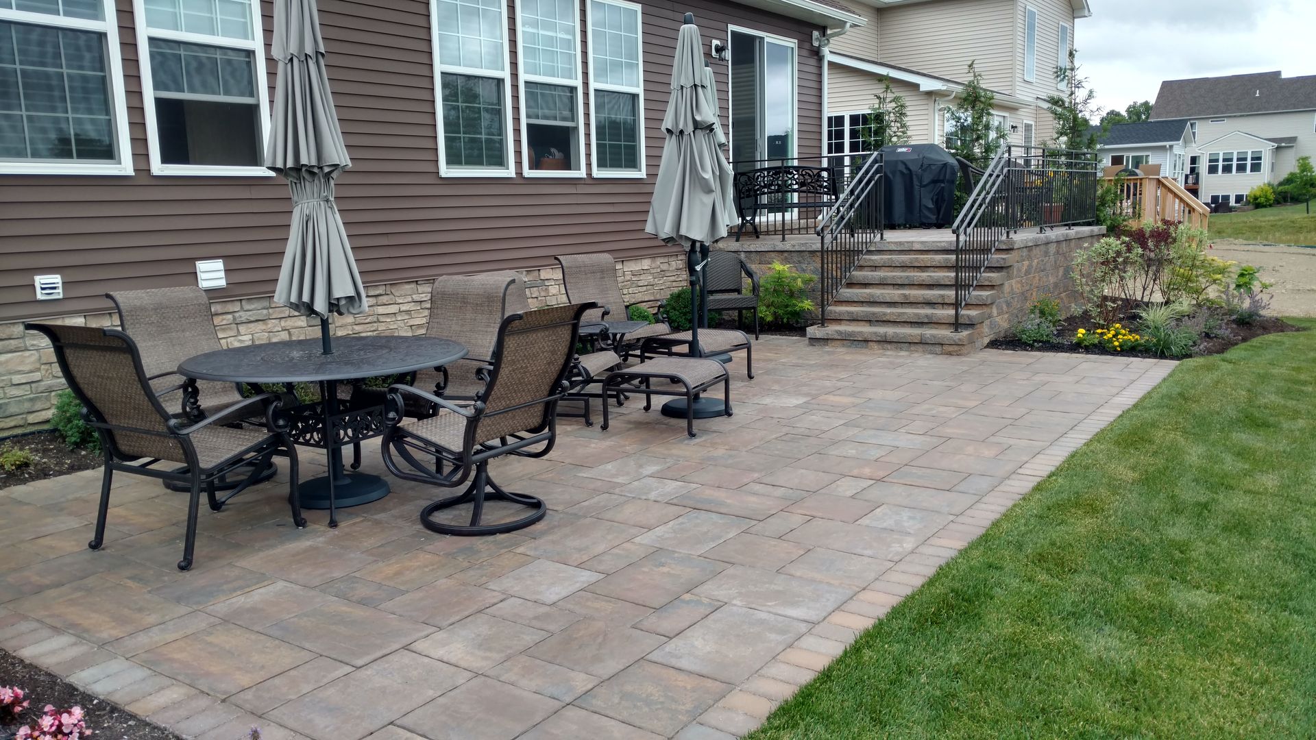 A patio with a table and chairs and umbrellas in front of a house.
