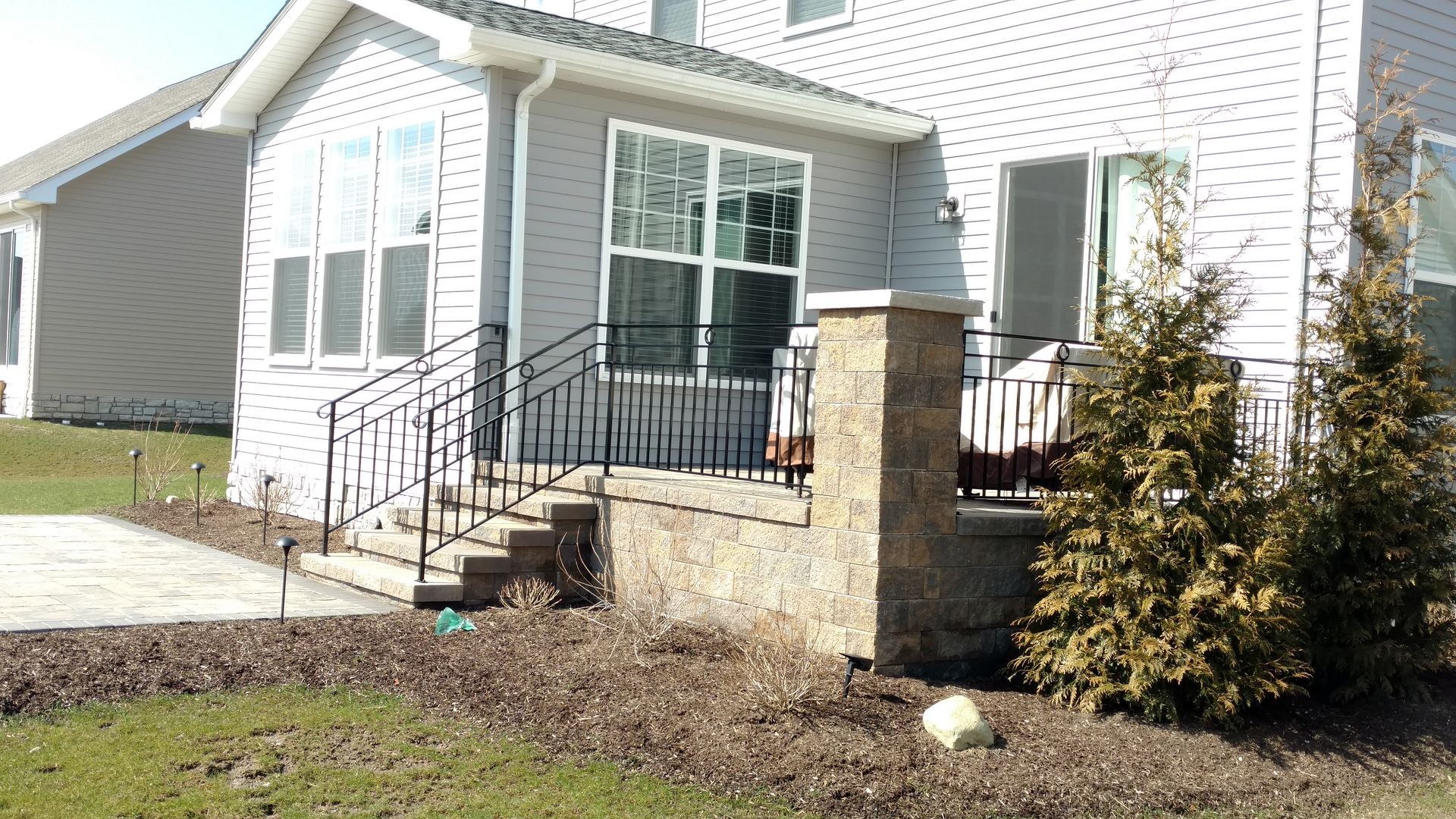 A white house with a stone pillar in front of it.