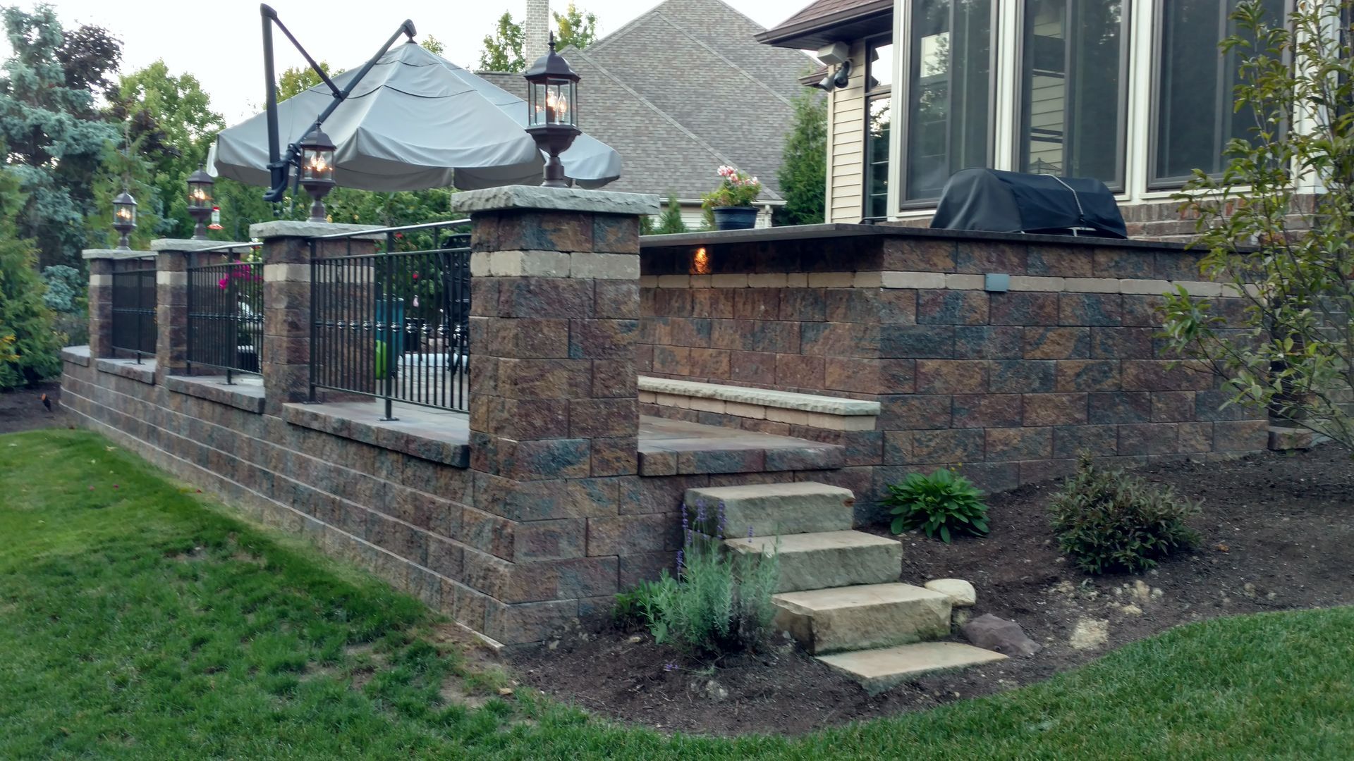 A brick wall with stairs leading up to a patio area in front of a house.