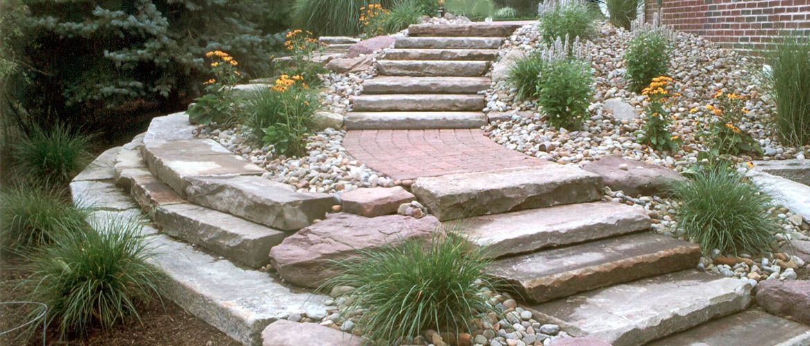 A set of stone stairs leading up to a house in a garden.