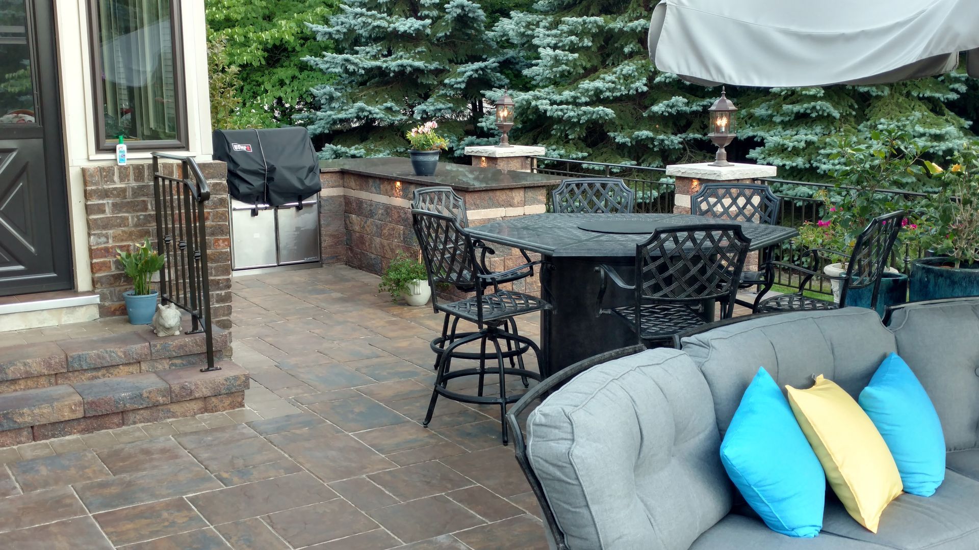 A patio with a couch , table , chairs and umbrella.