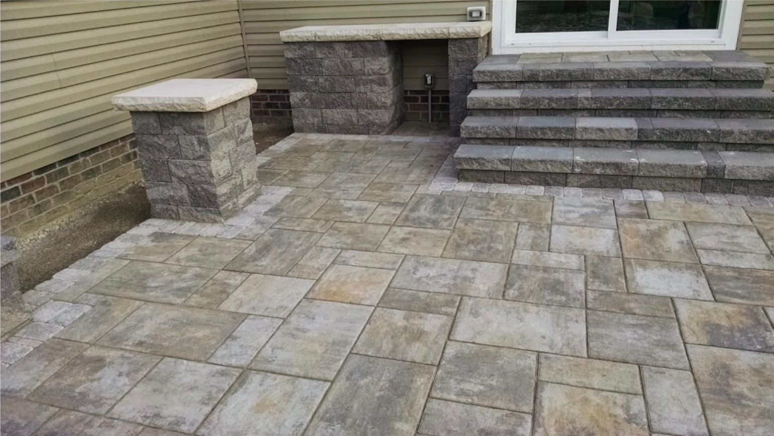 A patio with stairs and a pillar in front of a house.