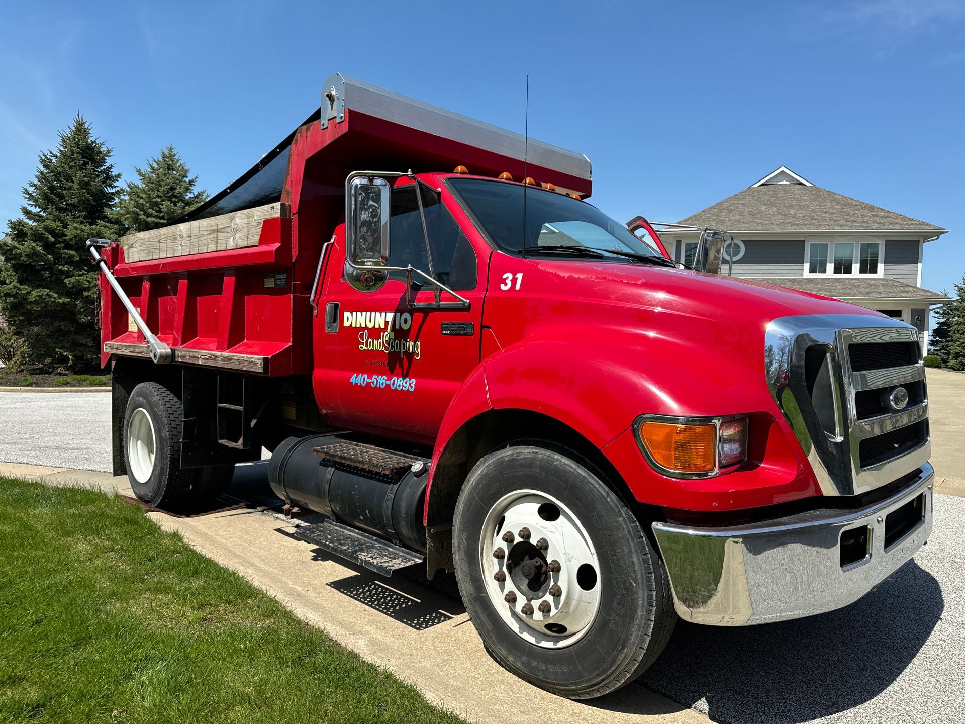 A red dump truck is parked on the side of the road in front of a house.