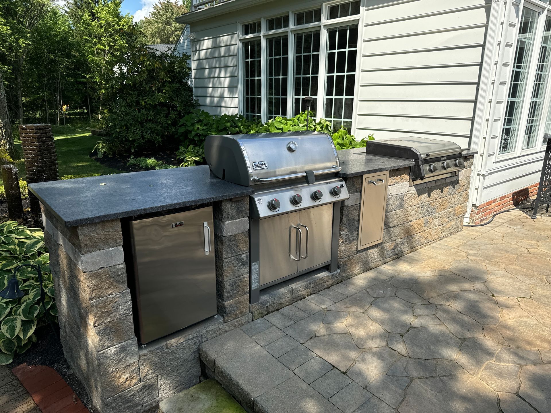 An outdoor kitchen with a grill and stools