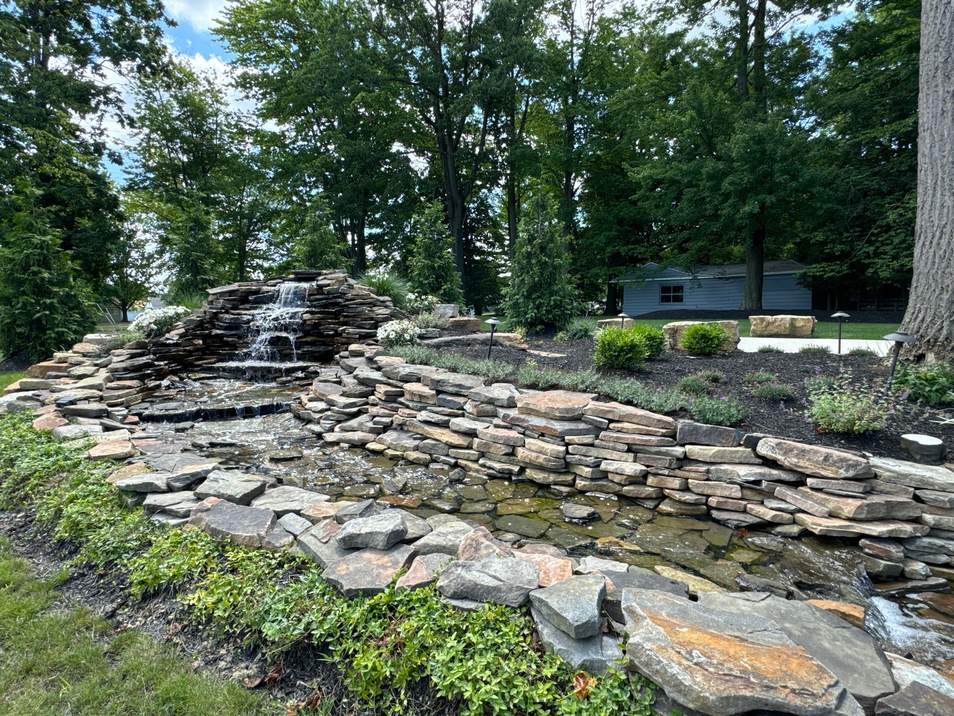 There is a waterfall in the middle of a pond surrounded by rocks.