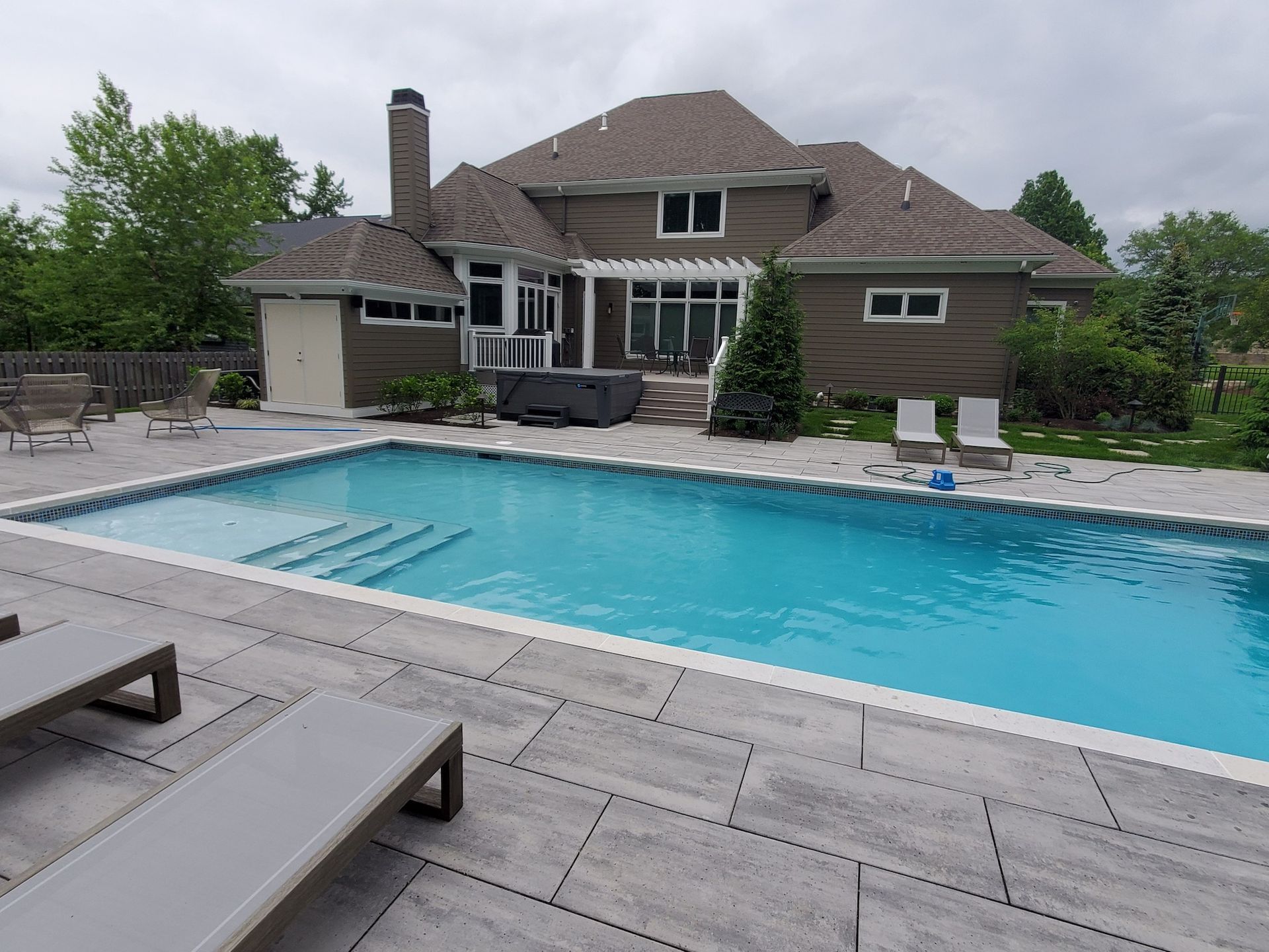 A large swimming pool is in the backyard of a house.