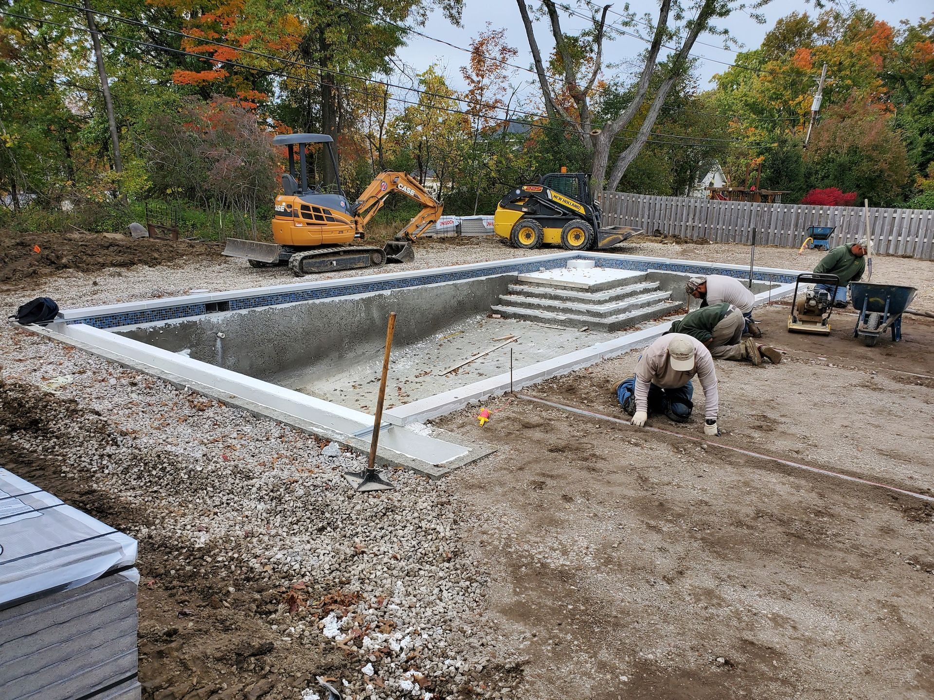 A group of construction workers are working on a swimming pool.