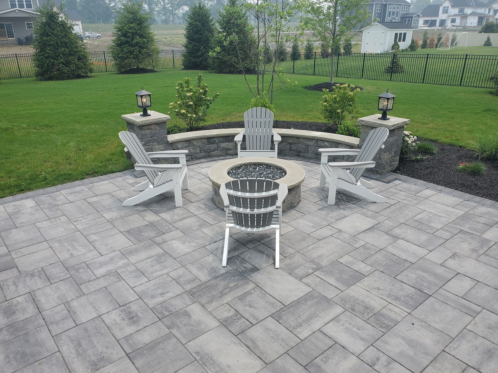 A fire pit is surrounded by chairs on a patio.