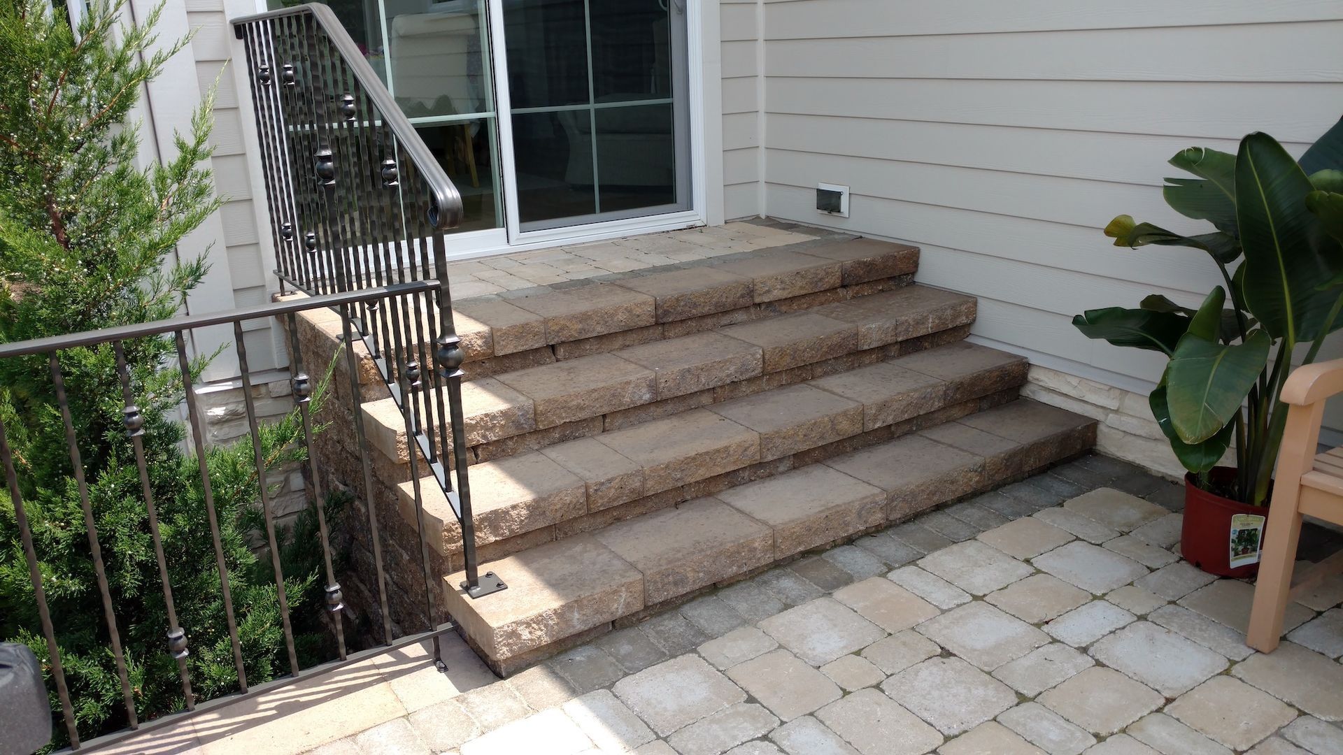 A set of stairs leading up to a patio with a wrought iron railing.