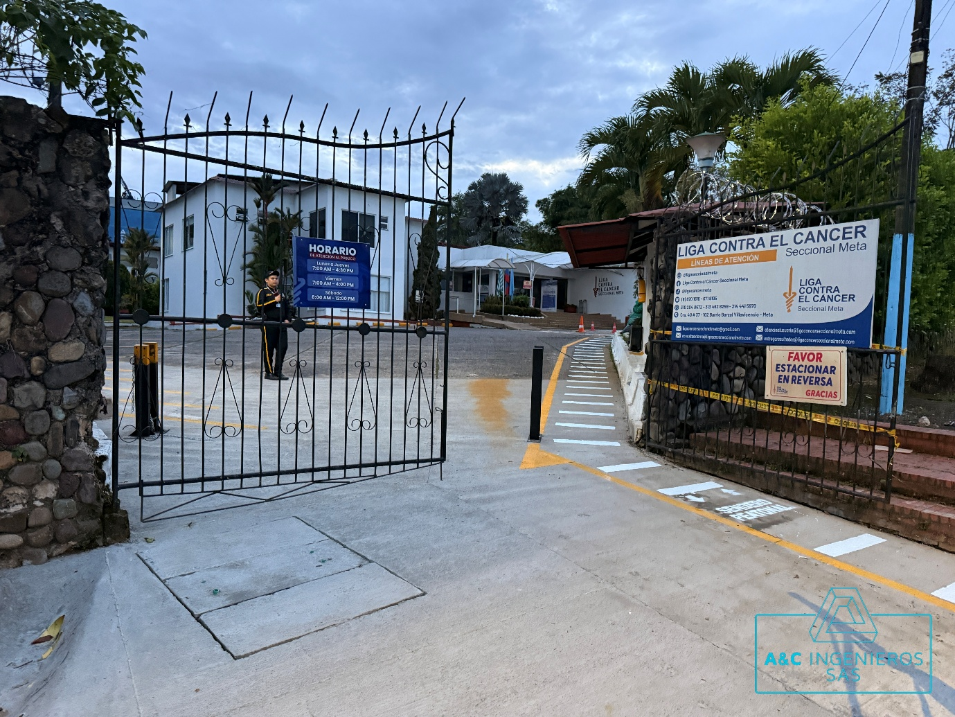 La puerta negra se abre a un edificio con carteles, entrada de concreto y una persona en el medio.