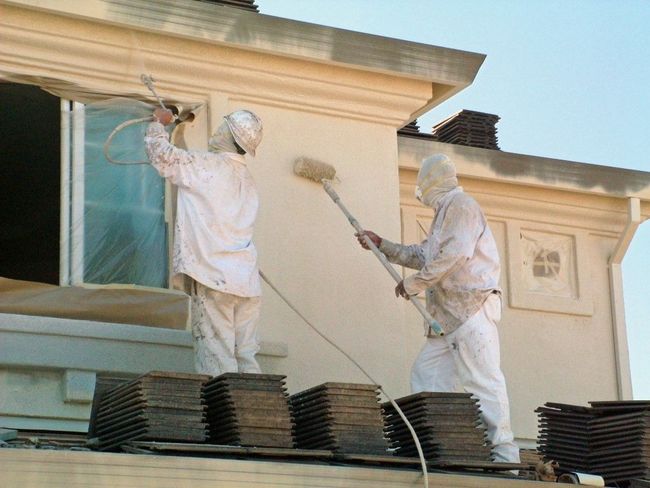 Two men are painting the side of a building