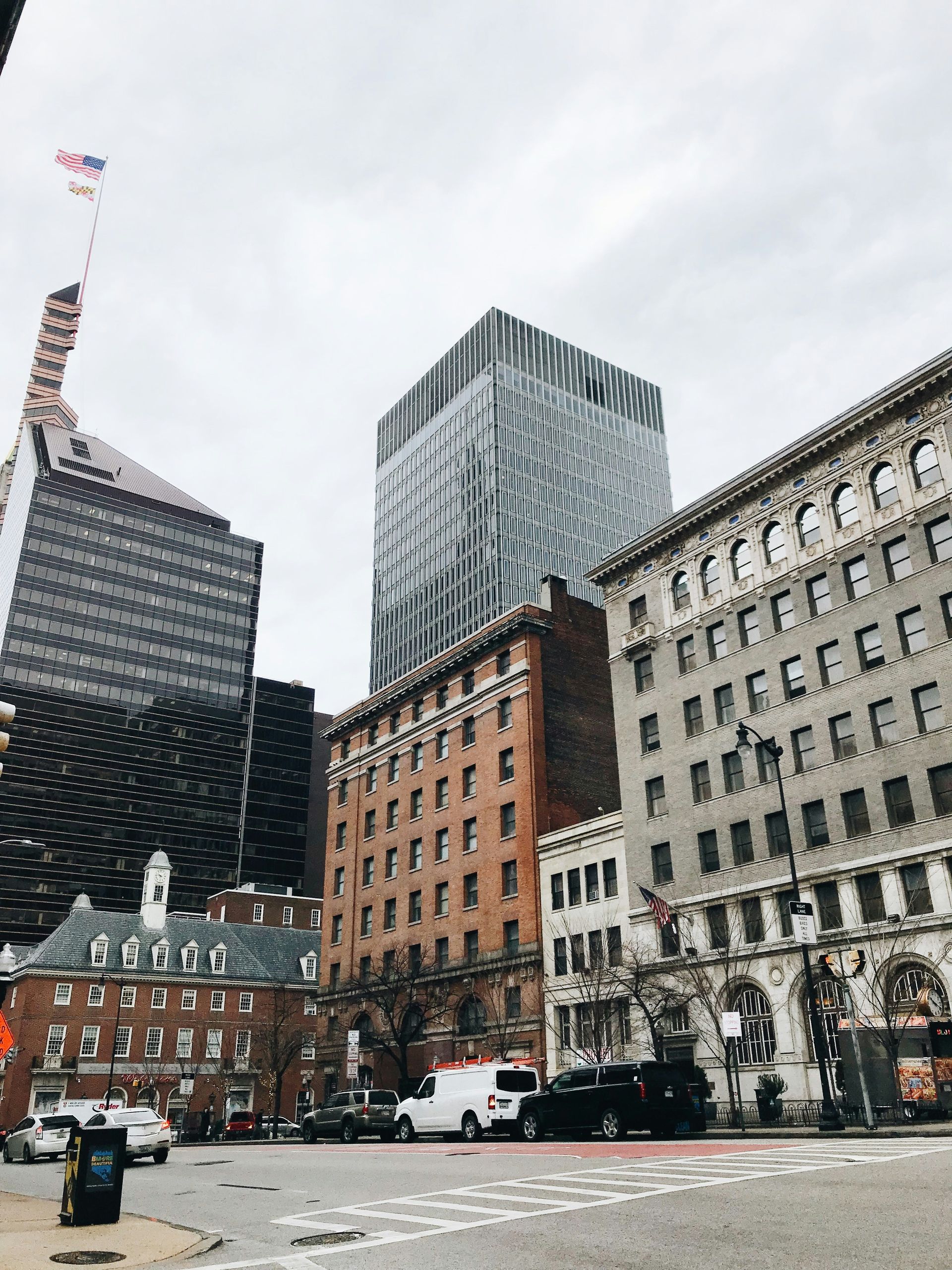 An urban street scene in Philadelphia featuring the tall, modern glass tower of the Comcast Technology Center.
