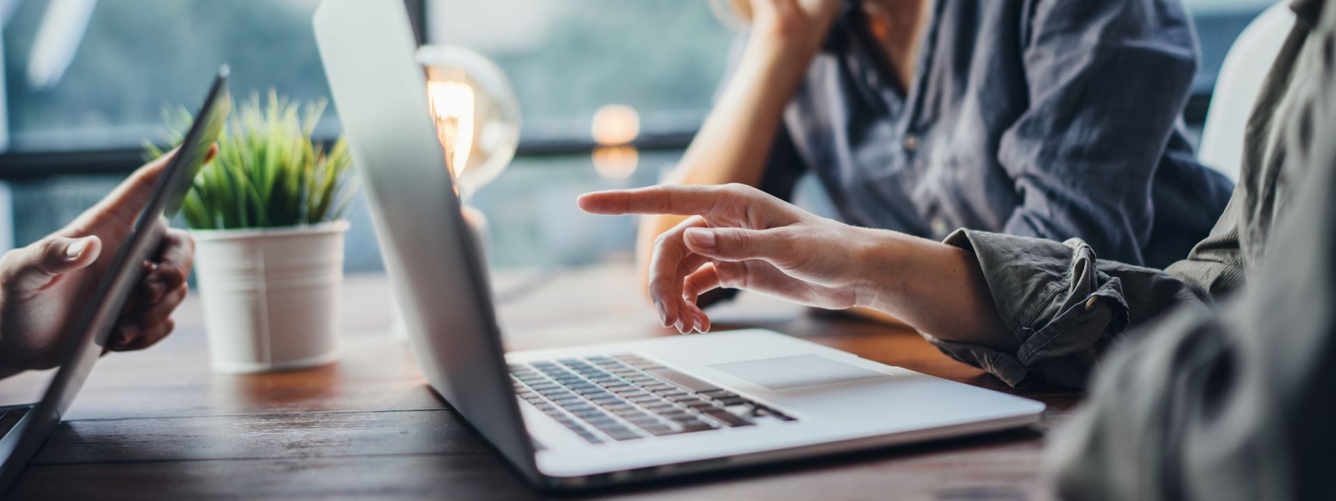 Hands typing on a laptop with a data center overlaid in the background.