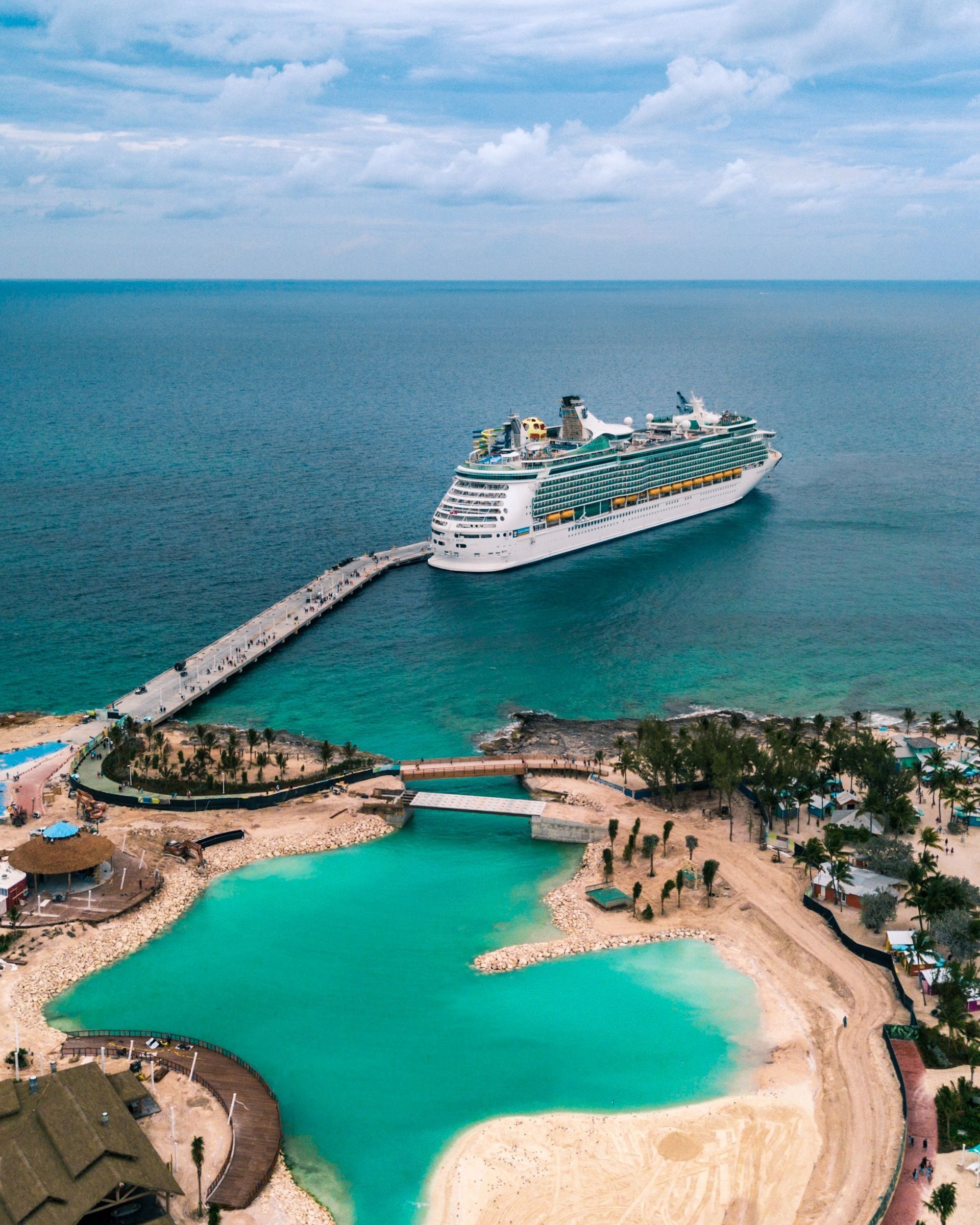 An aerial view of a cruise ship docked at a pier in the ocean.