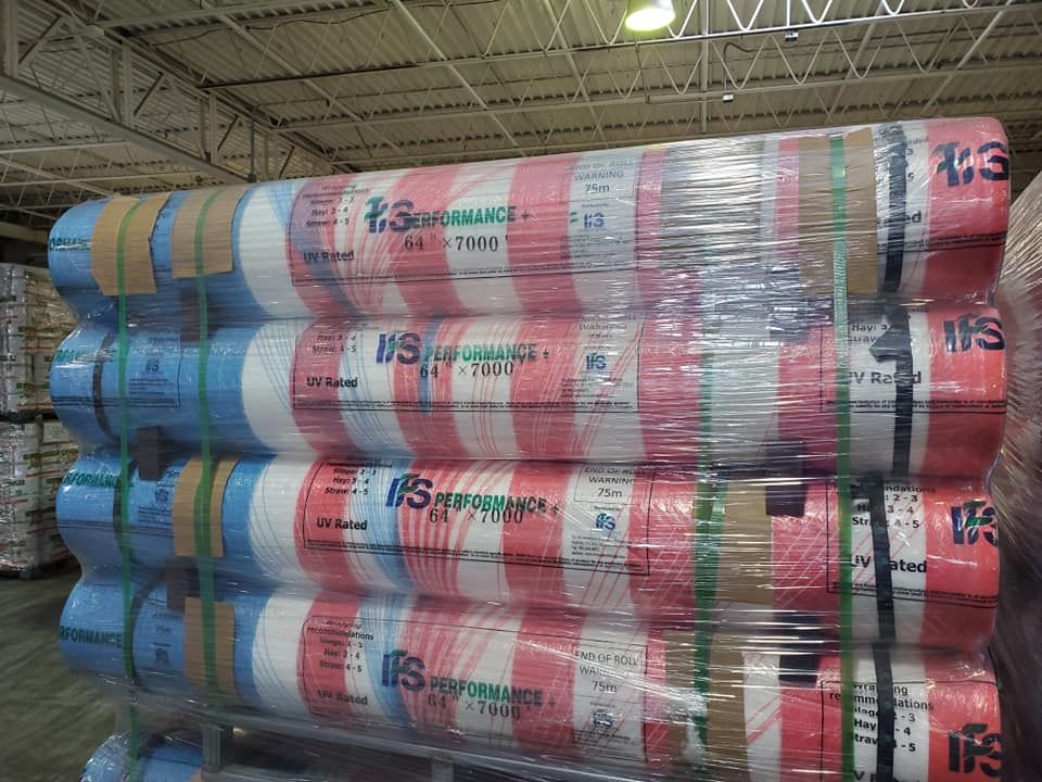 A bunch of rolls of plastic wrap are stacked on top of each other in a warehouse.