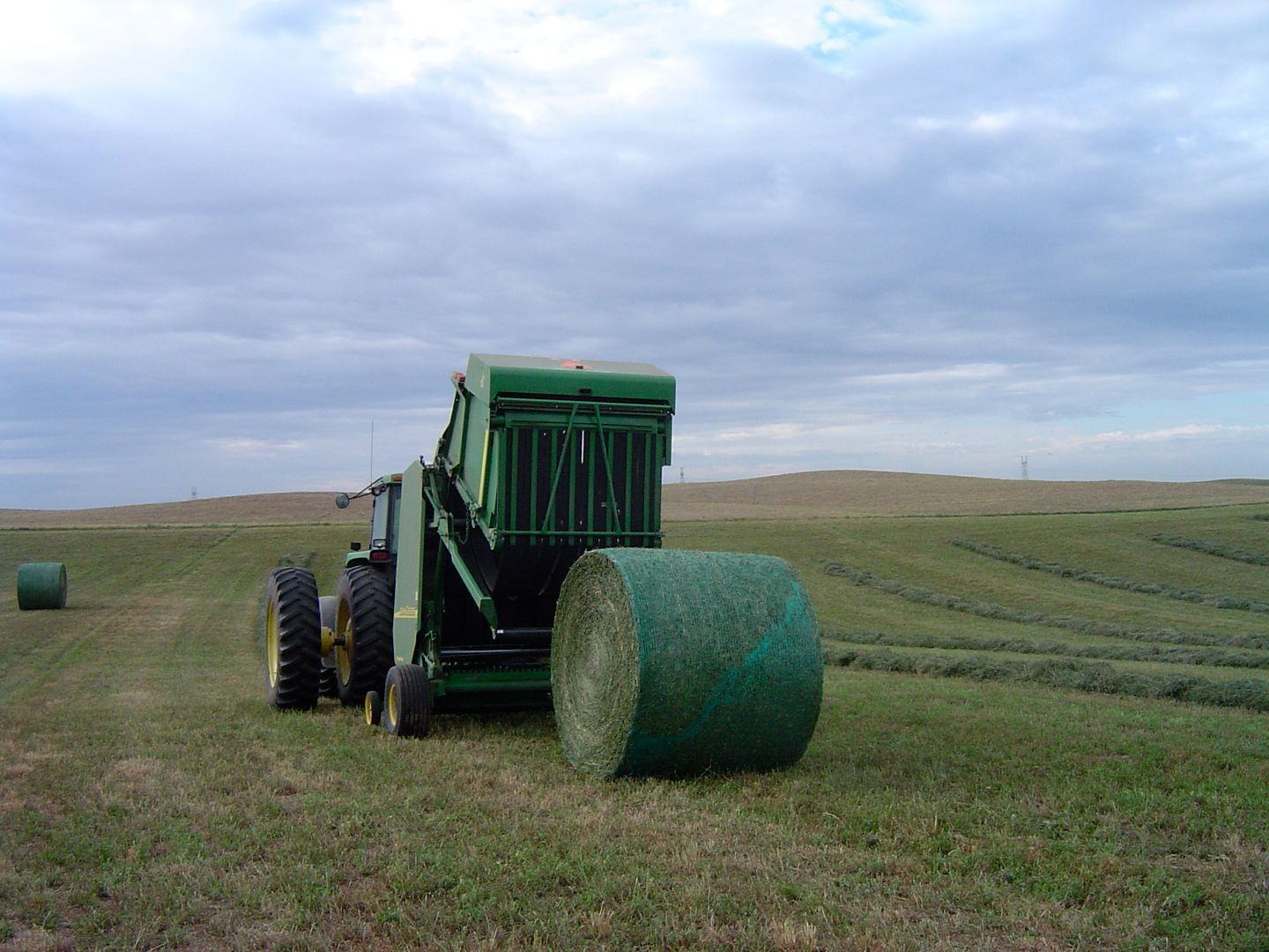 A john deere tractor is baling hay in a field