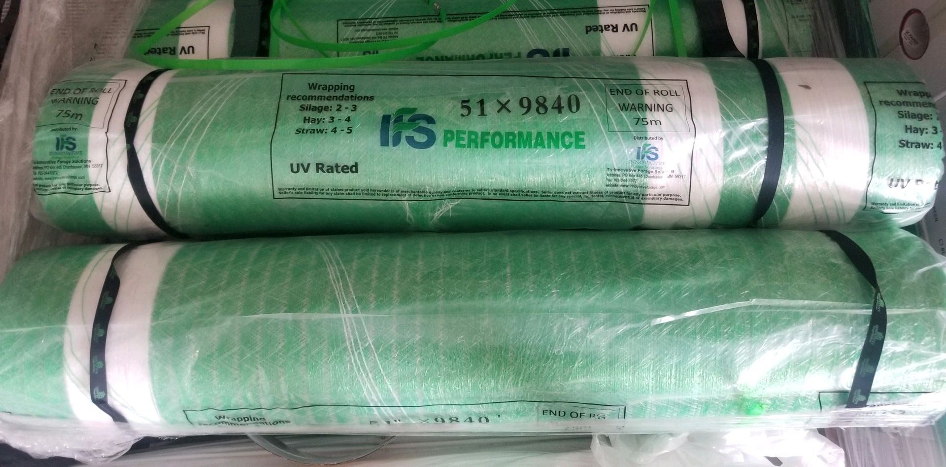 A bunch of green rolls of plastic sitting on top of each other on a table.