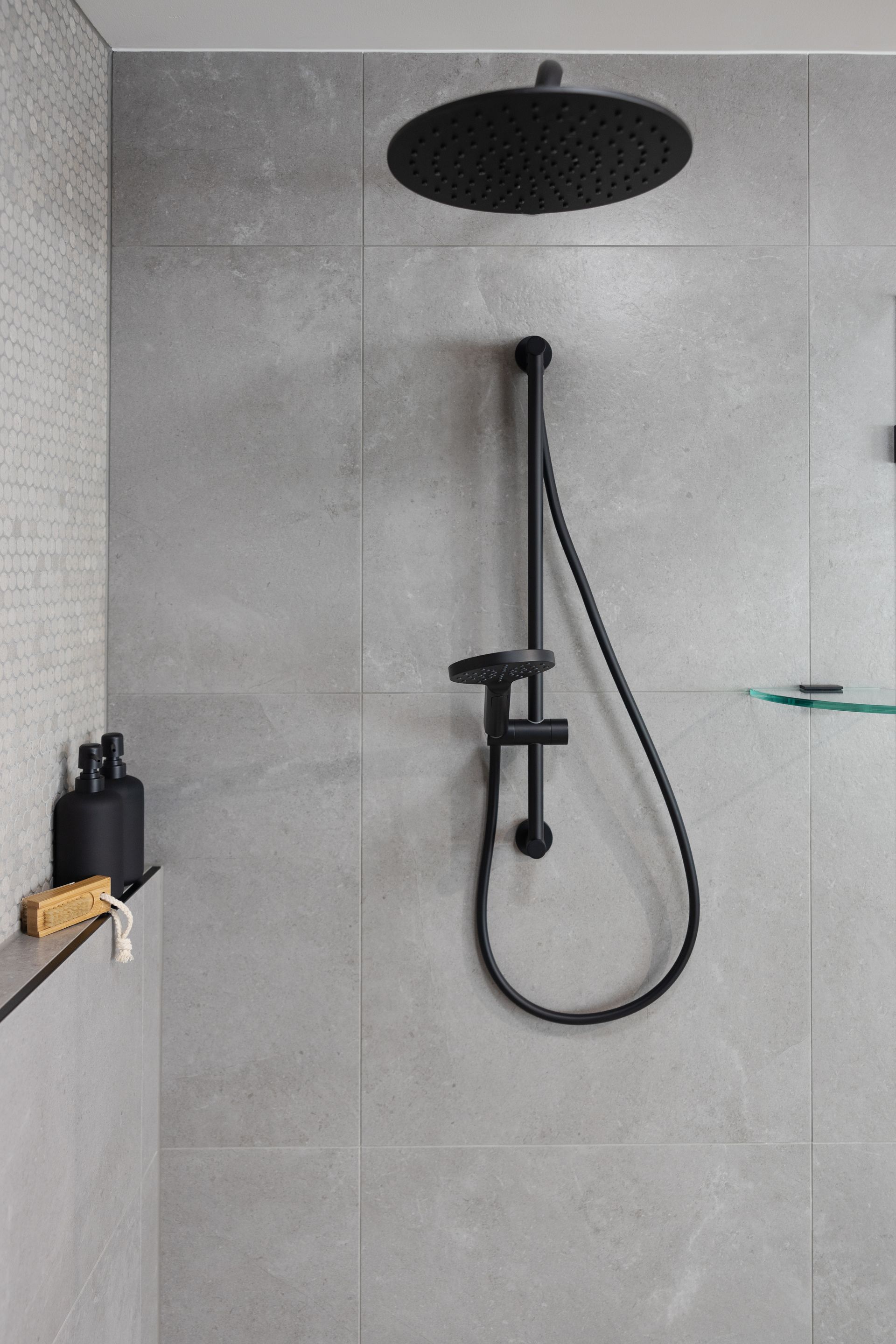 A shower with a black shower head and hose.