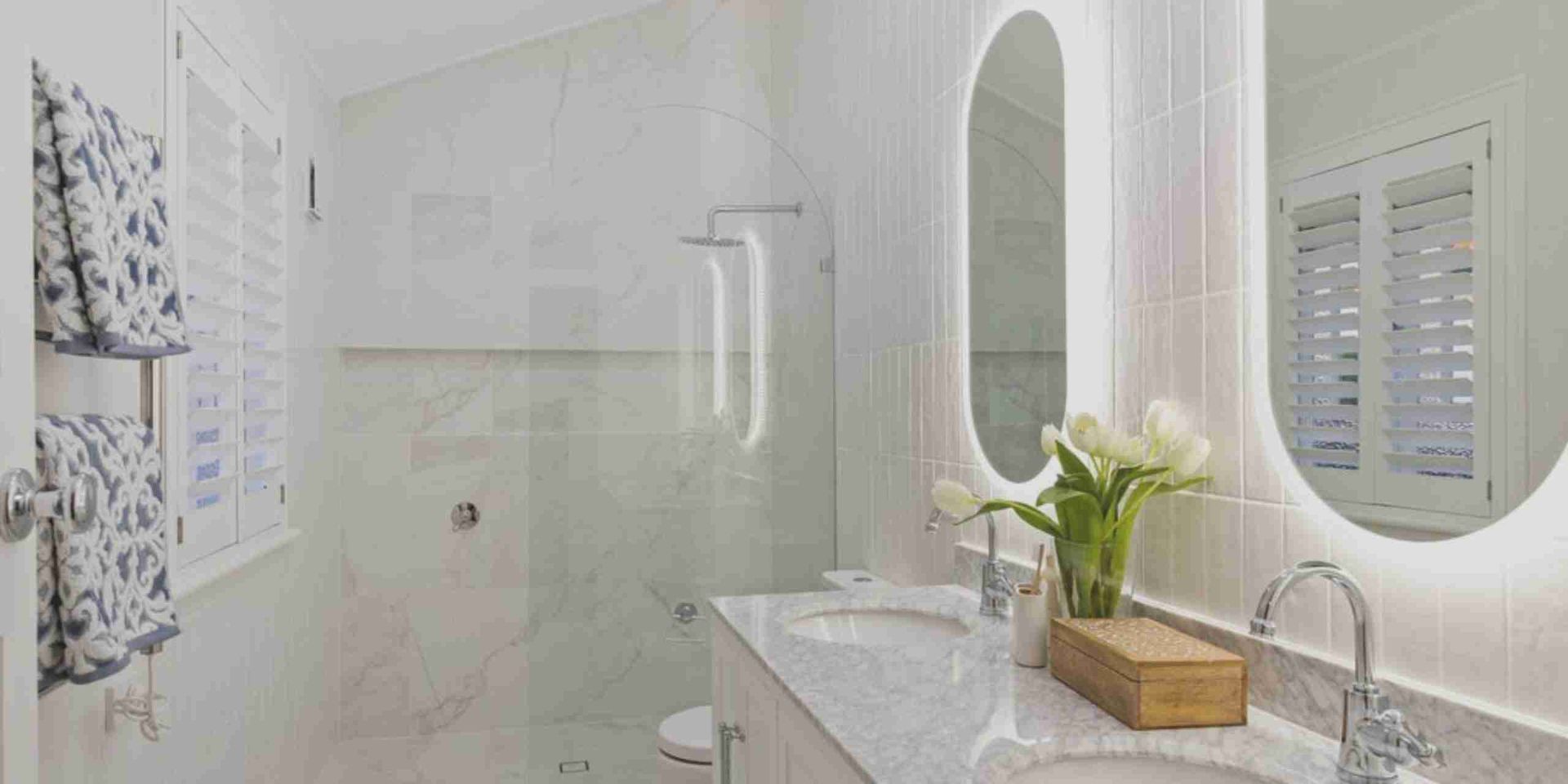 A bathroom with two sinks , a shower , and a mirror.