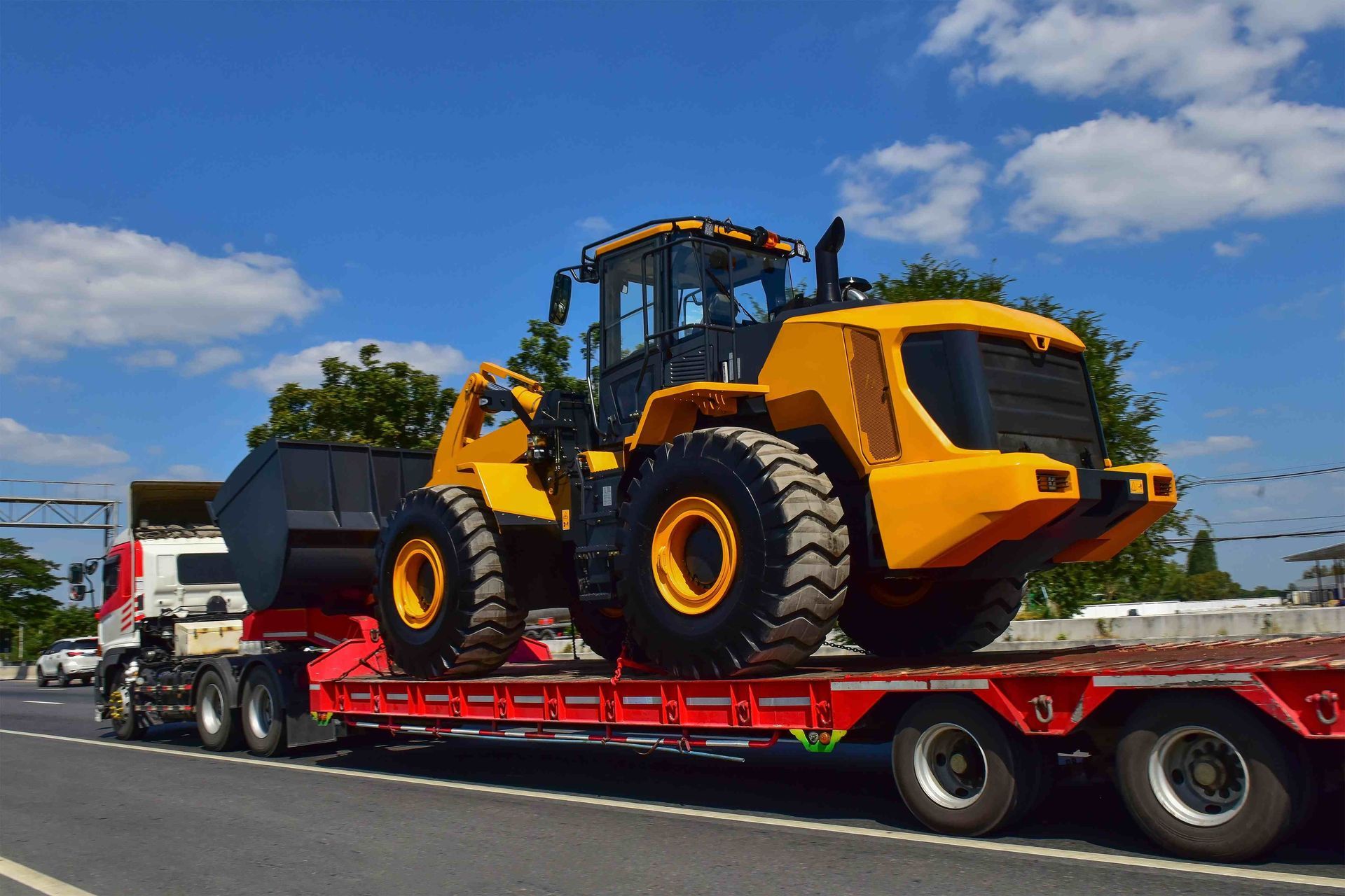 a yellow and black tractor is on a red trailer