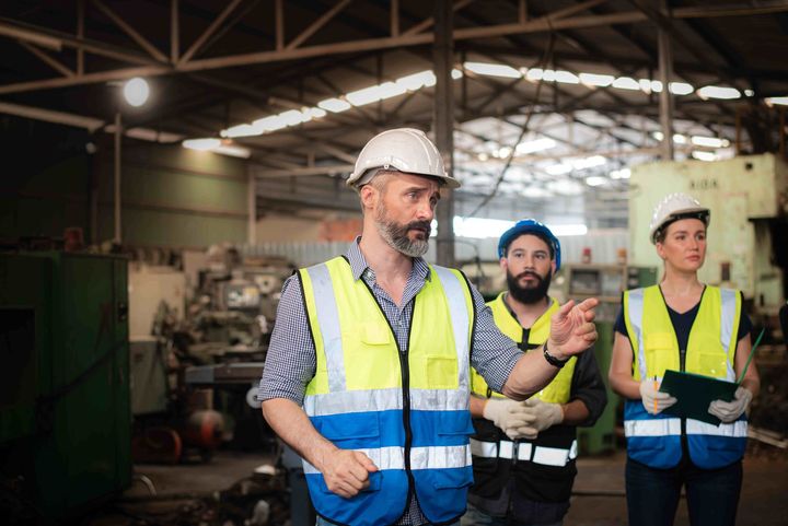 a man wearing a hard hat talks to a group of workers