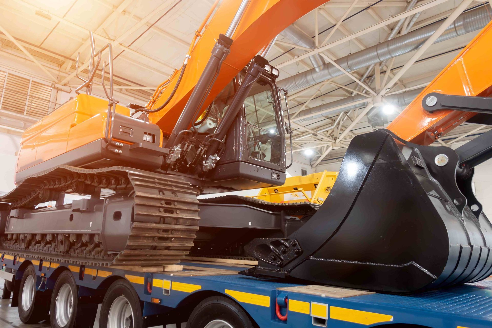 a large orange excavator sits on top of a blue trailer