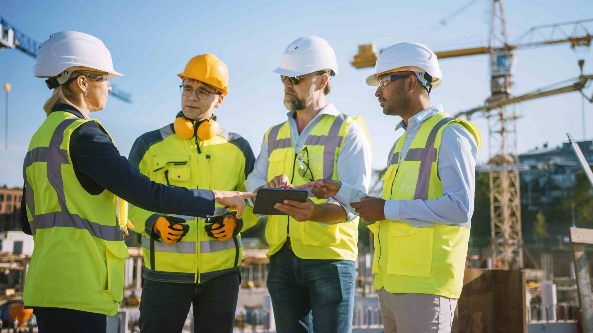 a group of construction workers are looking at a tablet