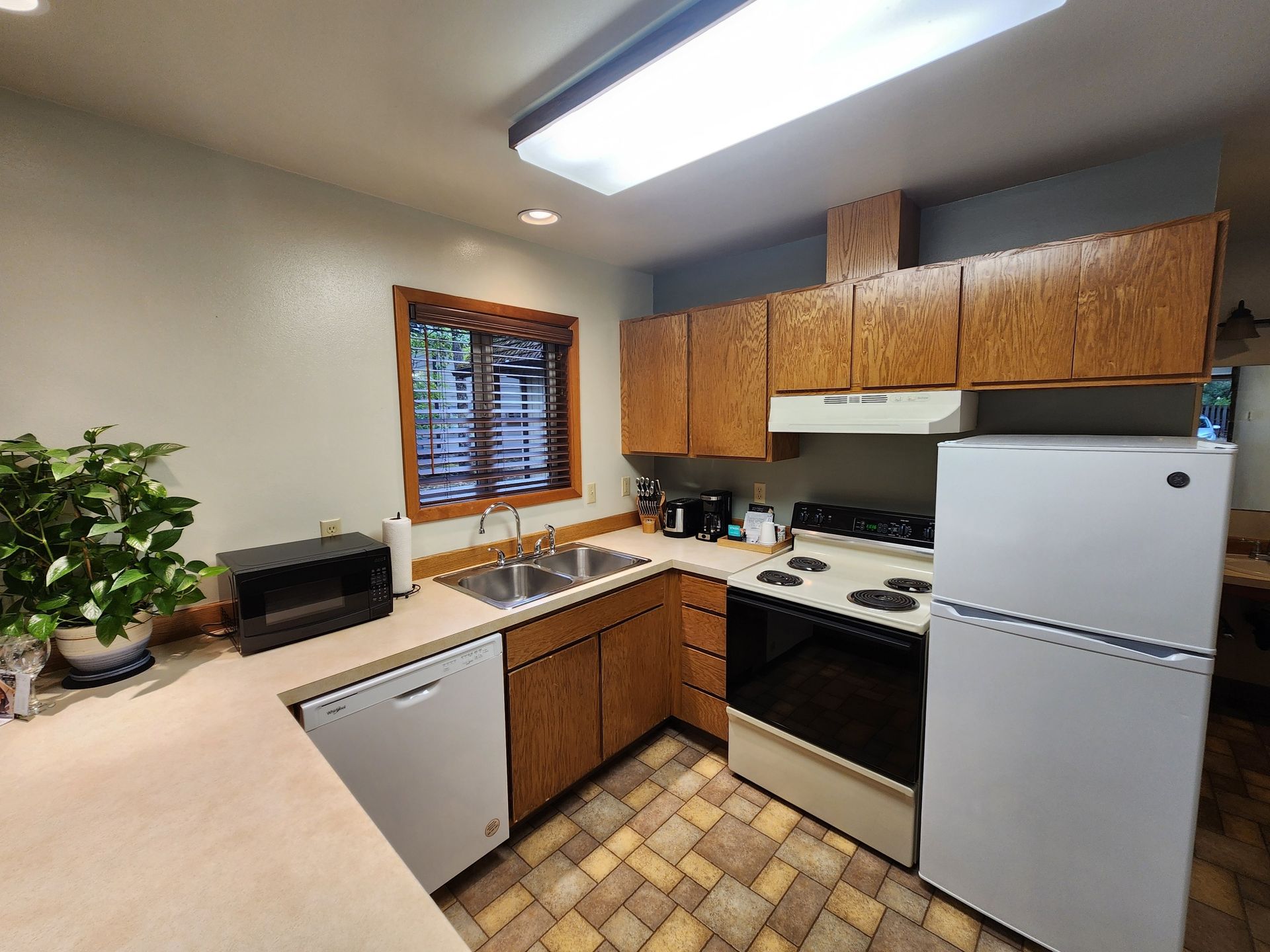 Kitchen with wood cabinets, white appliances, and a window above the sink.
