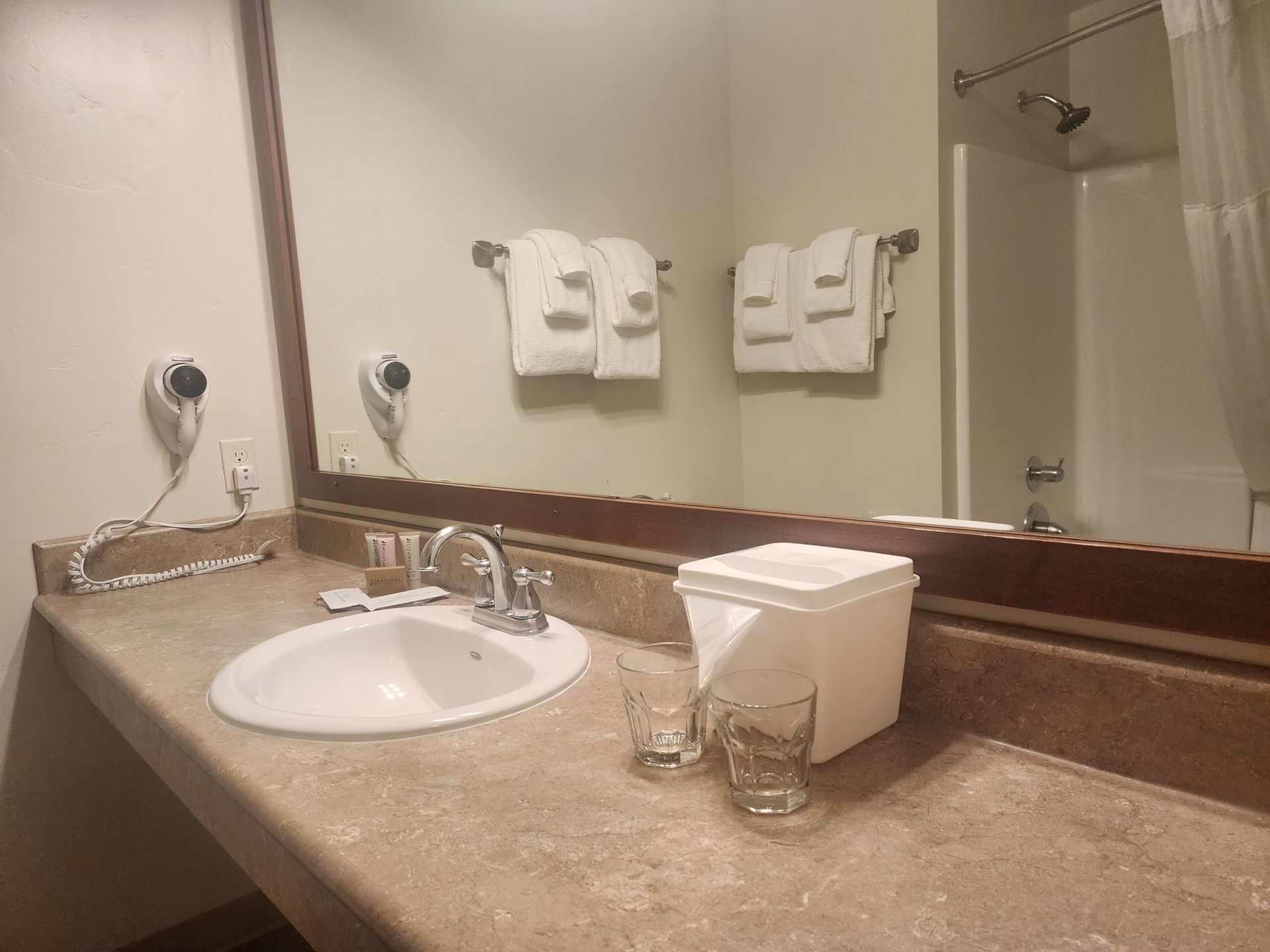 Bathroom with sink, mirror, and towels, featuring a bathtub with a shower curtain.