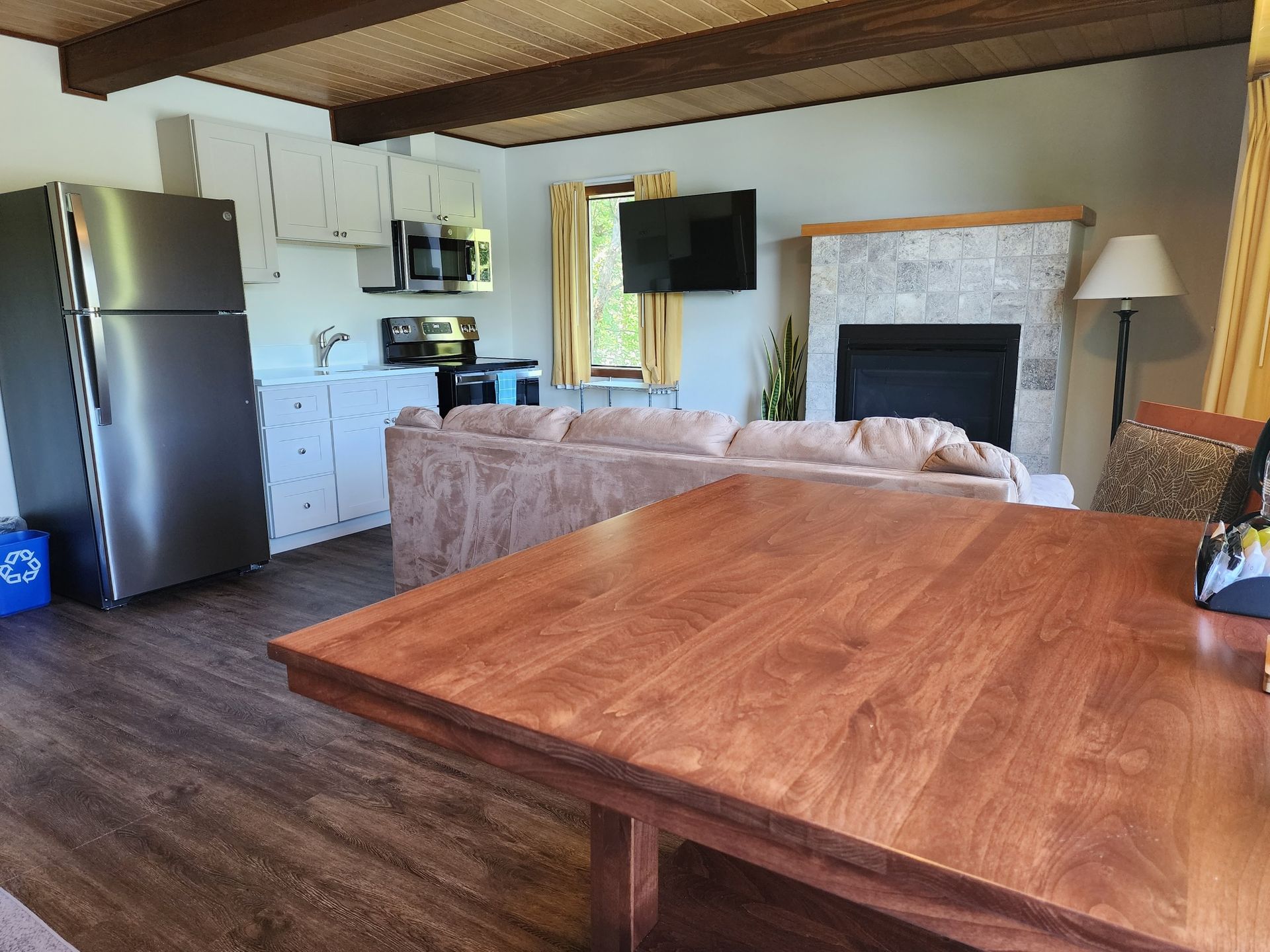 Cozy cabin interior with a kitchen, living area with fireplace, and a large wooden table.