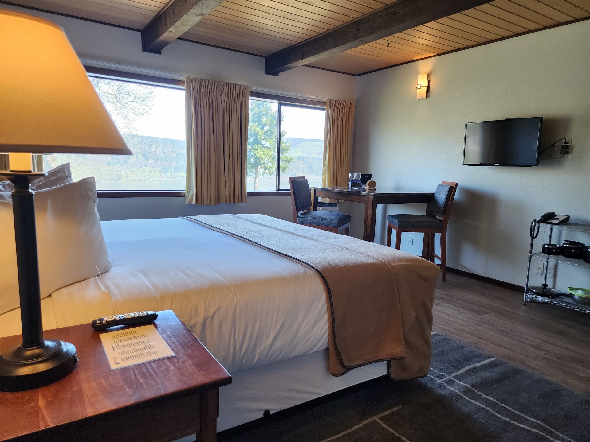 Bedroom with a bed, table, chairs, TV, and window overlooking a landscape.
