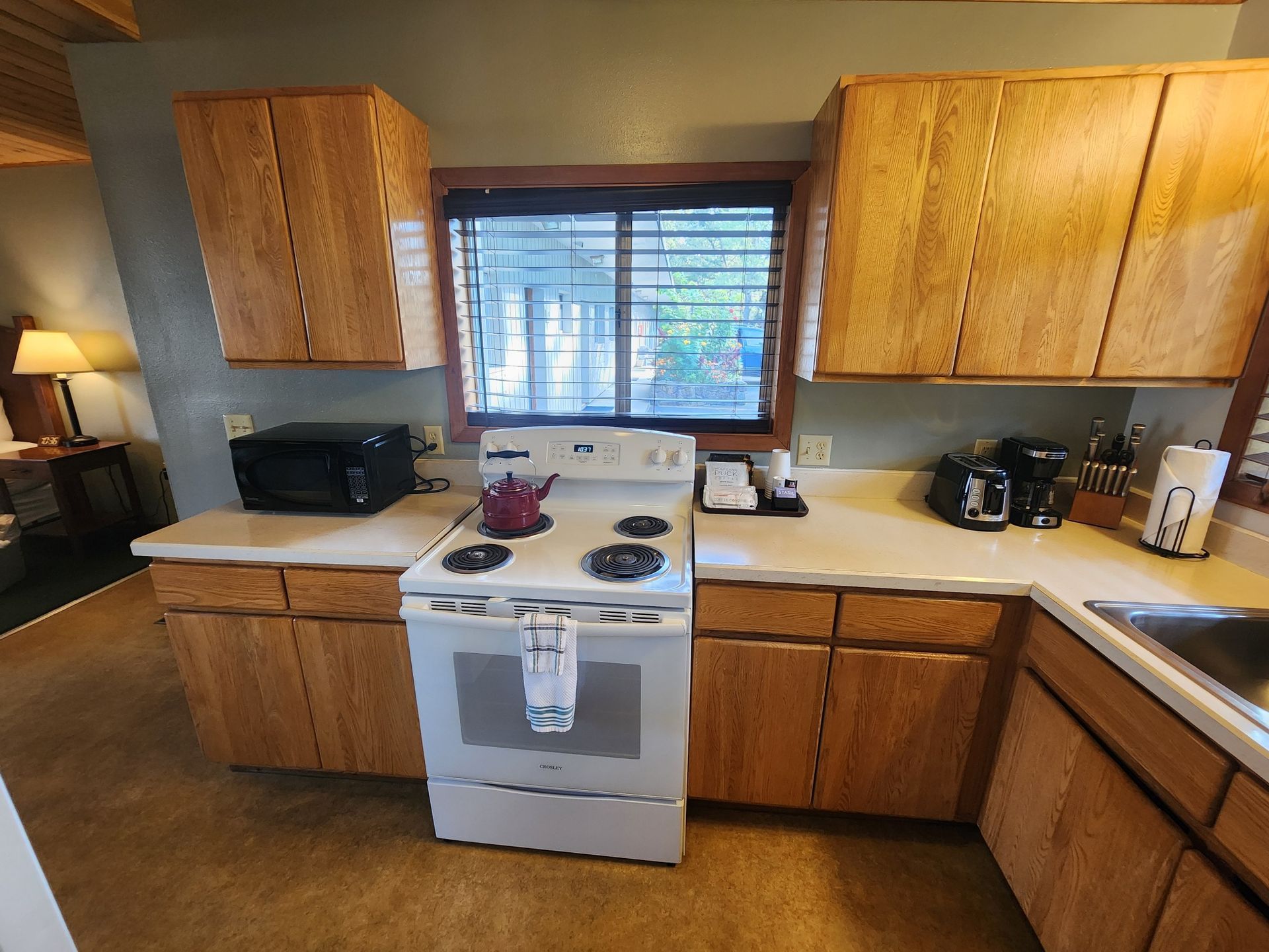 Kitchen with light wood cabinets, white appliances, and a window.