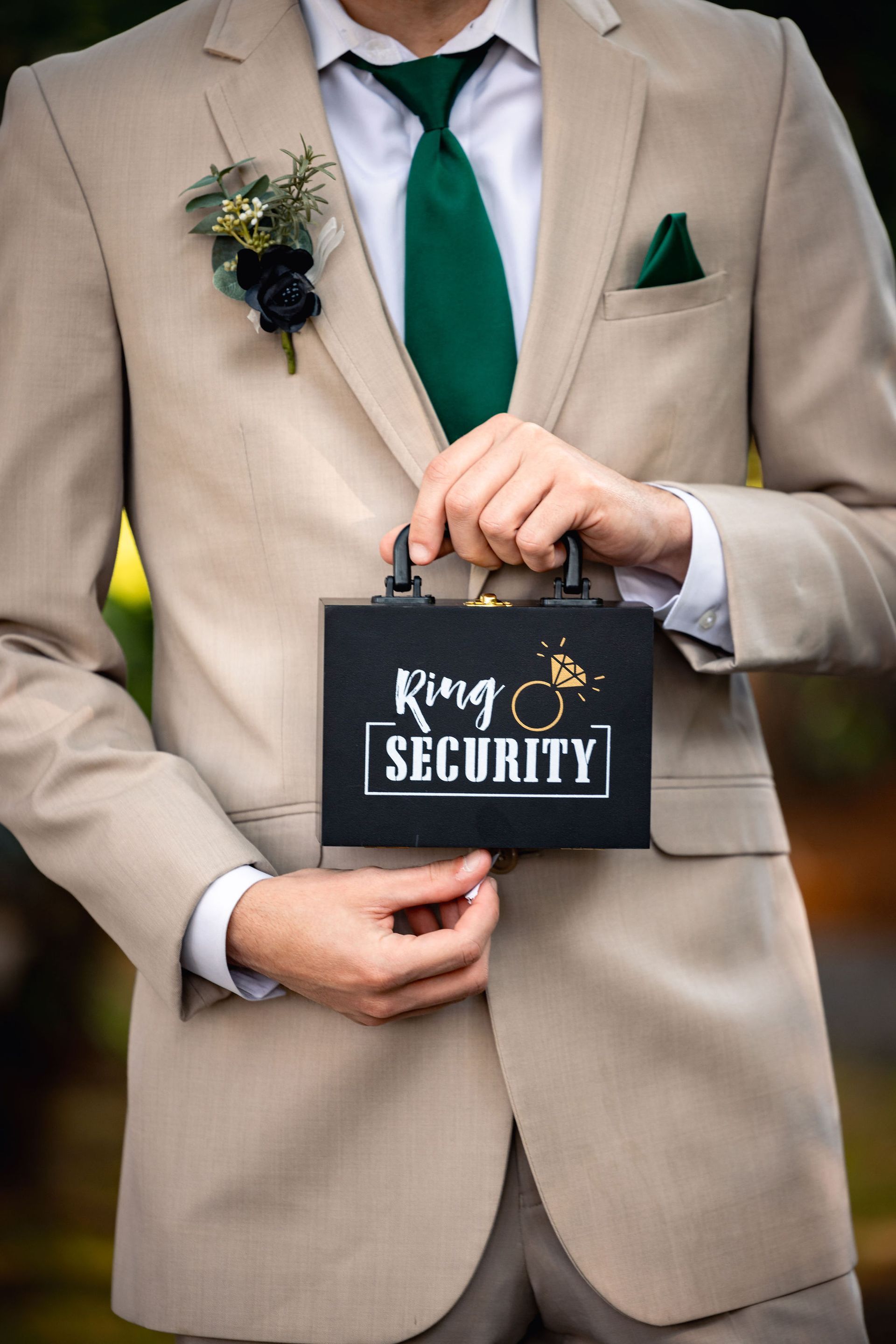Person in tan suit holding a black box labeled 