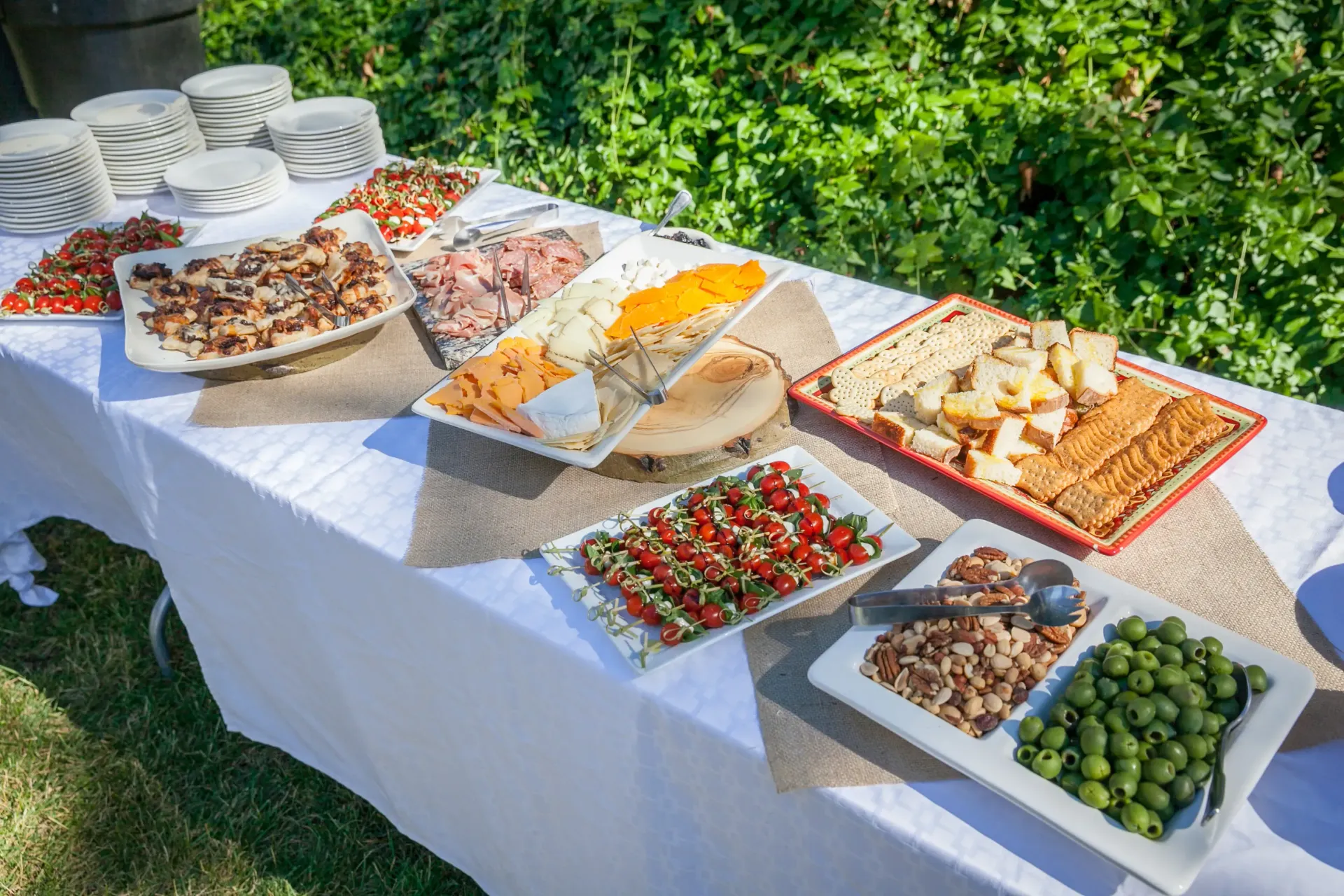 Buffet table outdoors with various appetizers and plates.