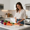 A person in a white button-down shirt chops a piece of raw steak on a cutting board surrounded by fresh vegetables.