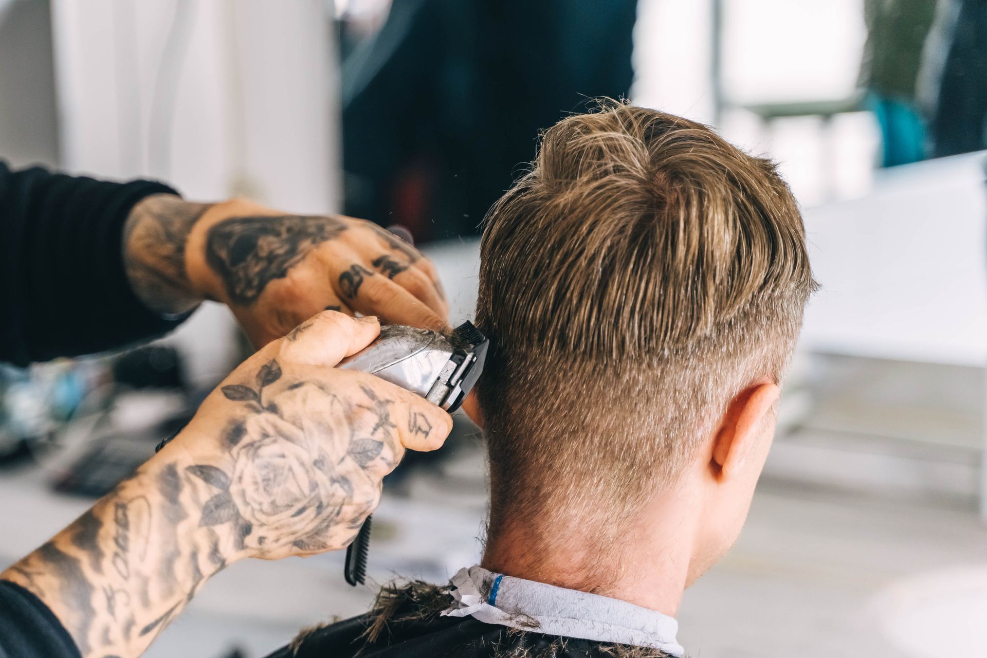 Barber giving a man a haircut with electric clippers.