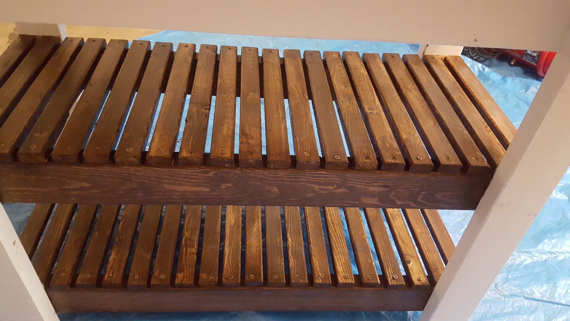 A wooden shelf is sitting on top of a blue tarp.