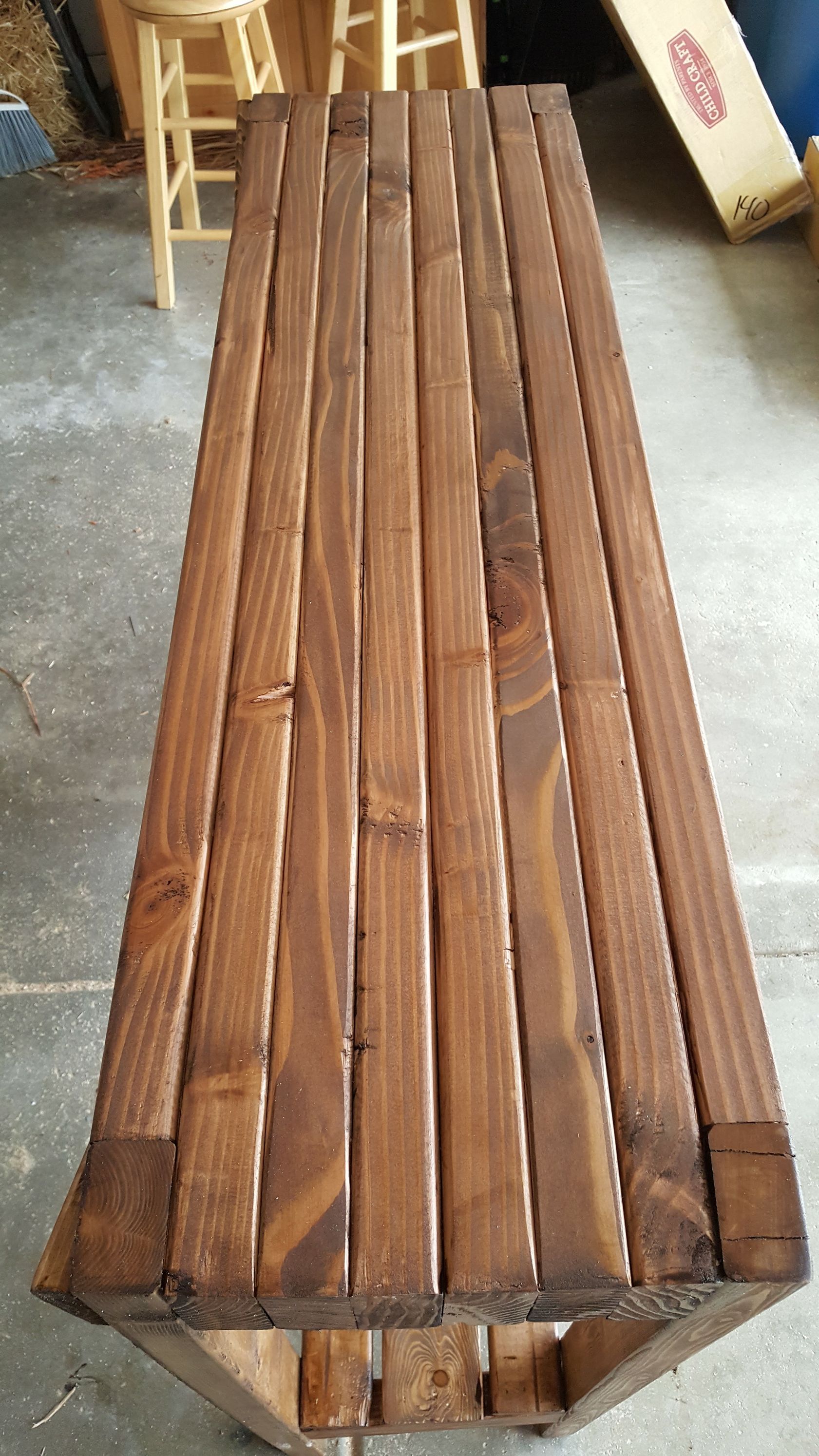 A wooden bench is sitting on a concrete floor in a garage.