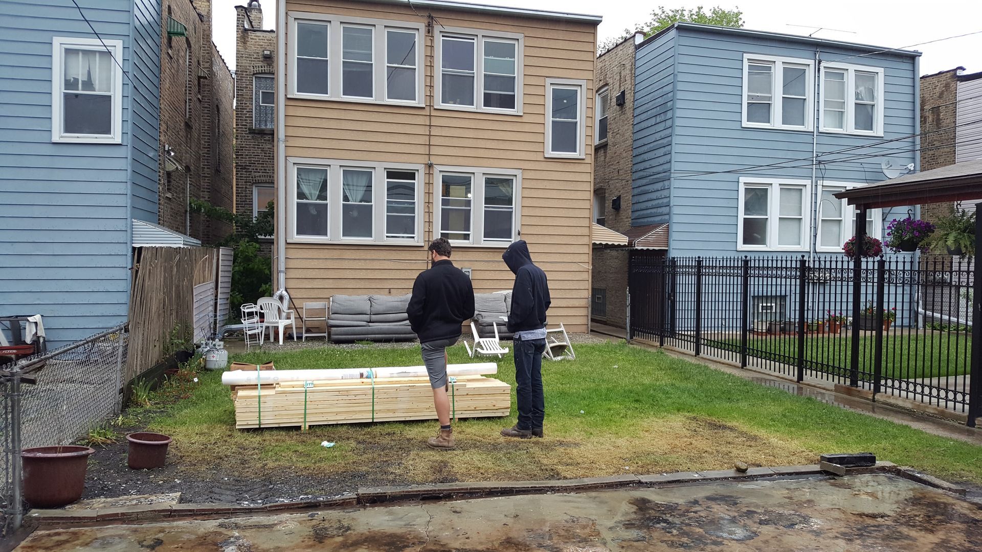 Two men are standing in the grass in front of a house.