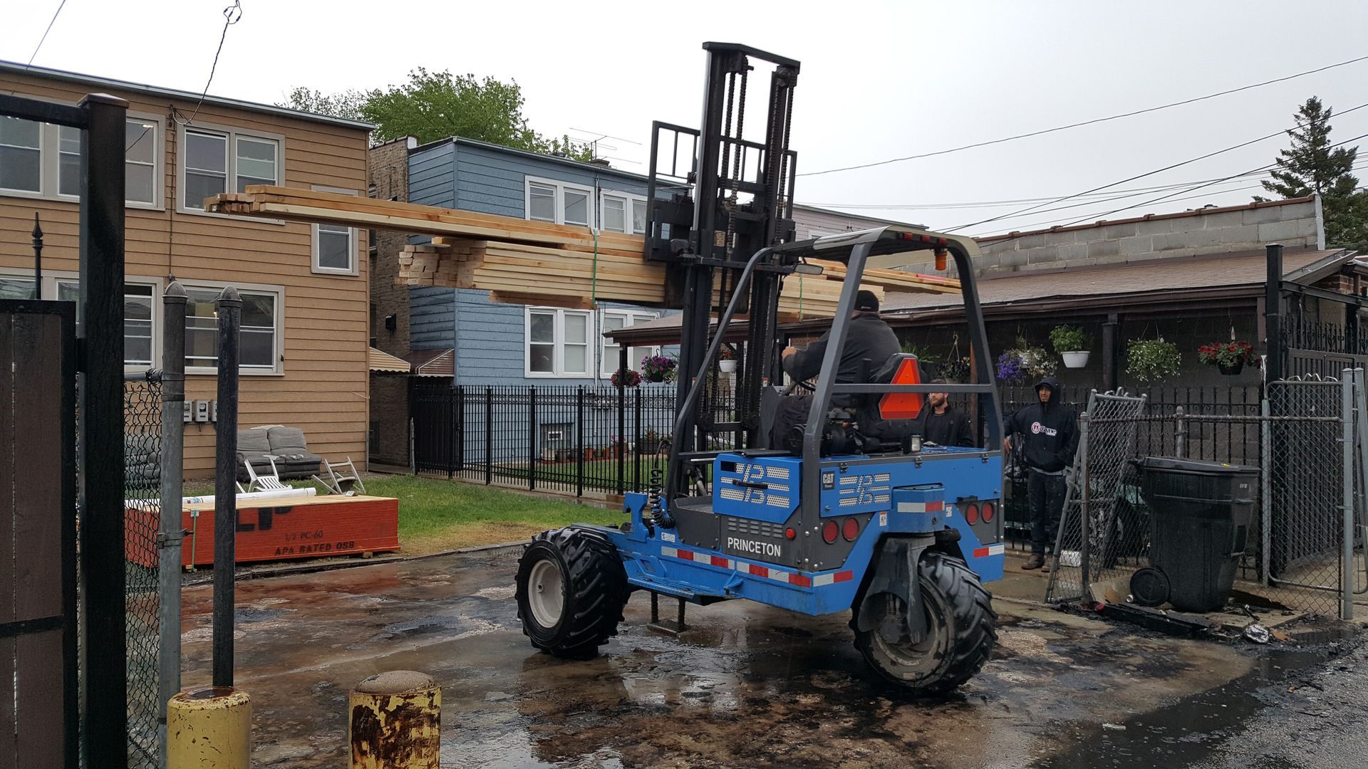 A blue forklift is parked in front of a building.