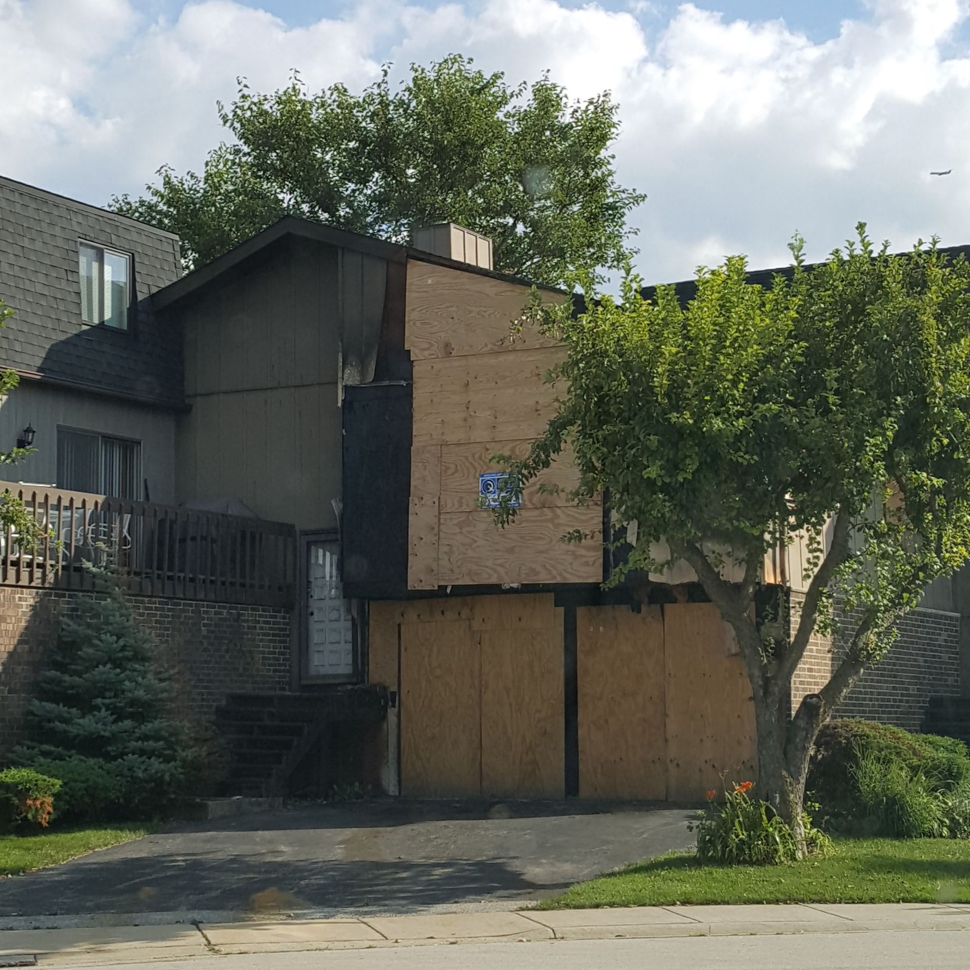 A house with a tree in front of it that is boarded up