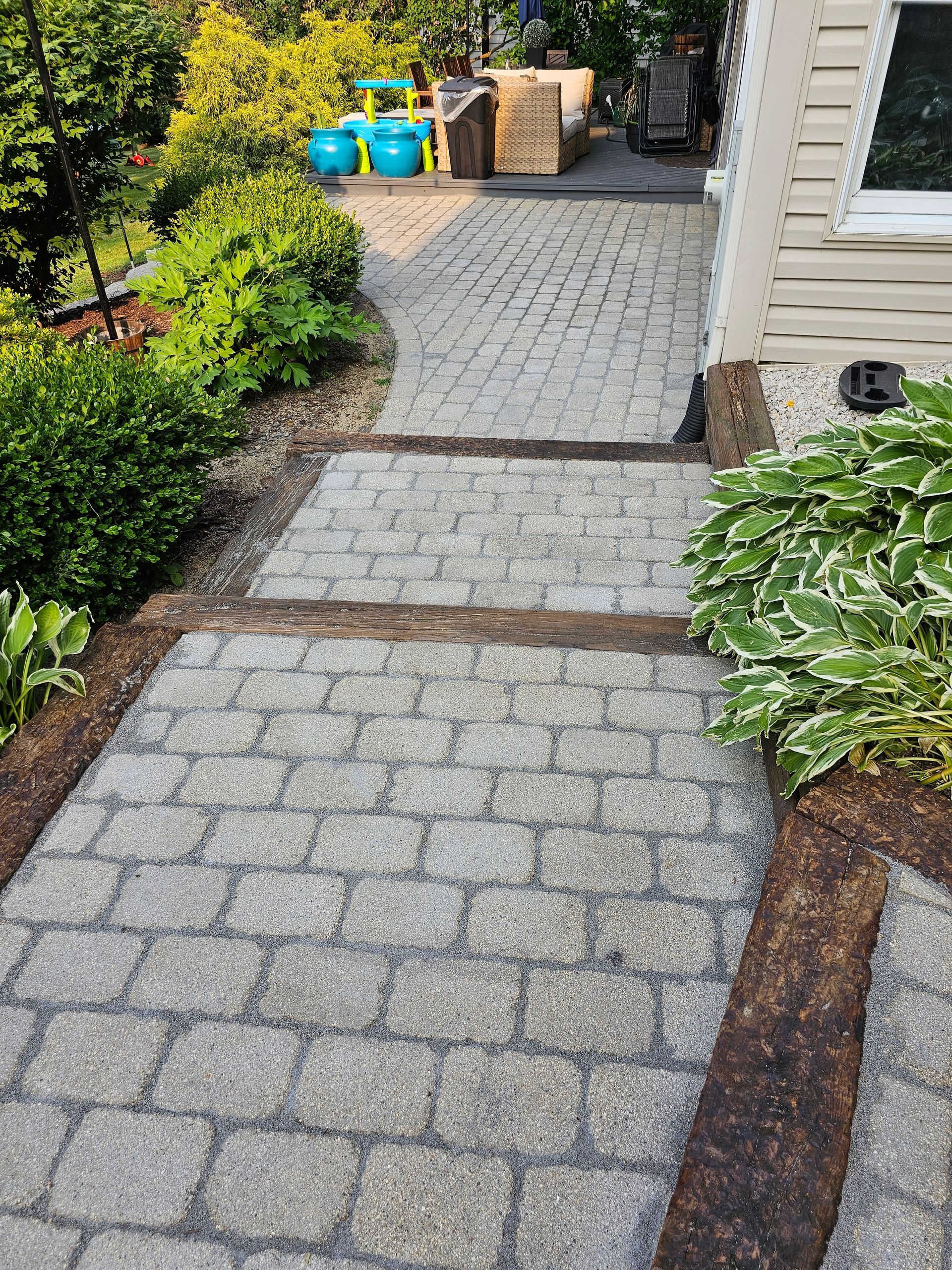 A brick walkway leading to a patio and a house.