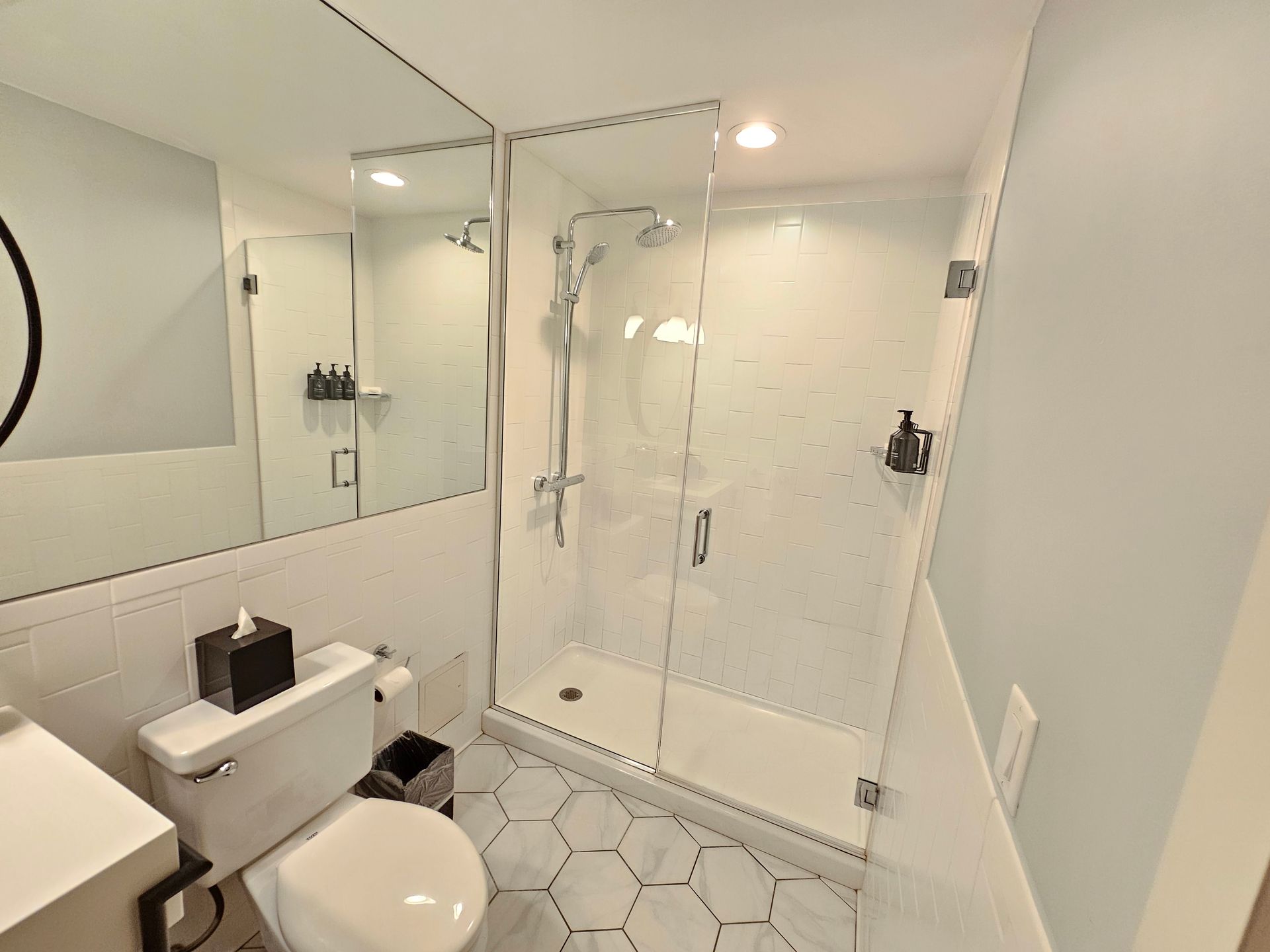 A bathroom with a toilet , sink , shower and mirror.