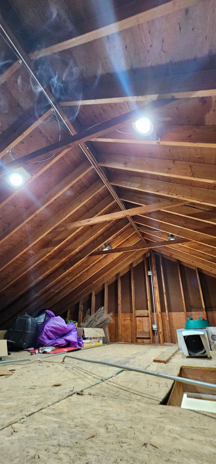 An attic with a lot of wooden beams and a ceiling fan.
