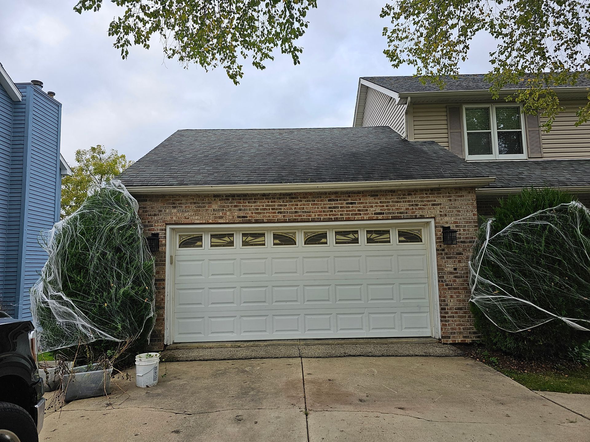A white garage door is sitting in front of a brick house.