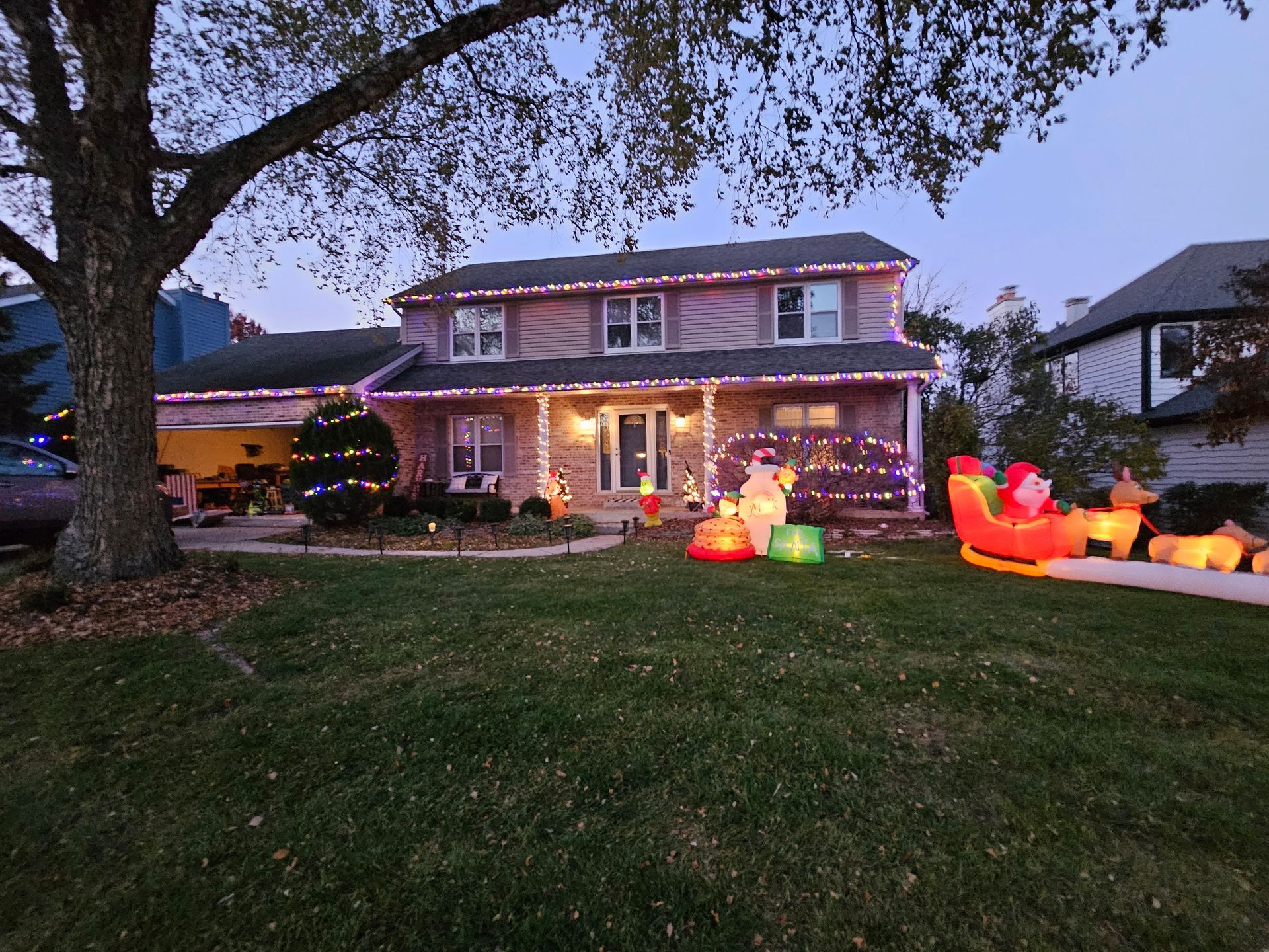 A house decorated for christmas with a santa sleigh in the front yard.