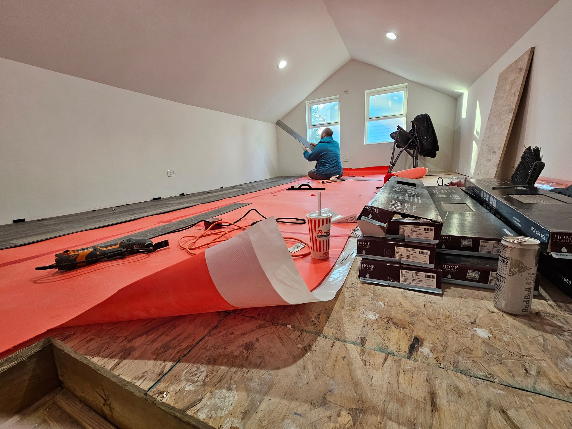 A man is sitting on a wooden floor in a room.