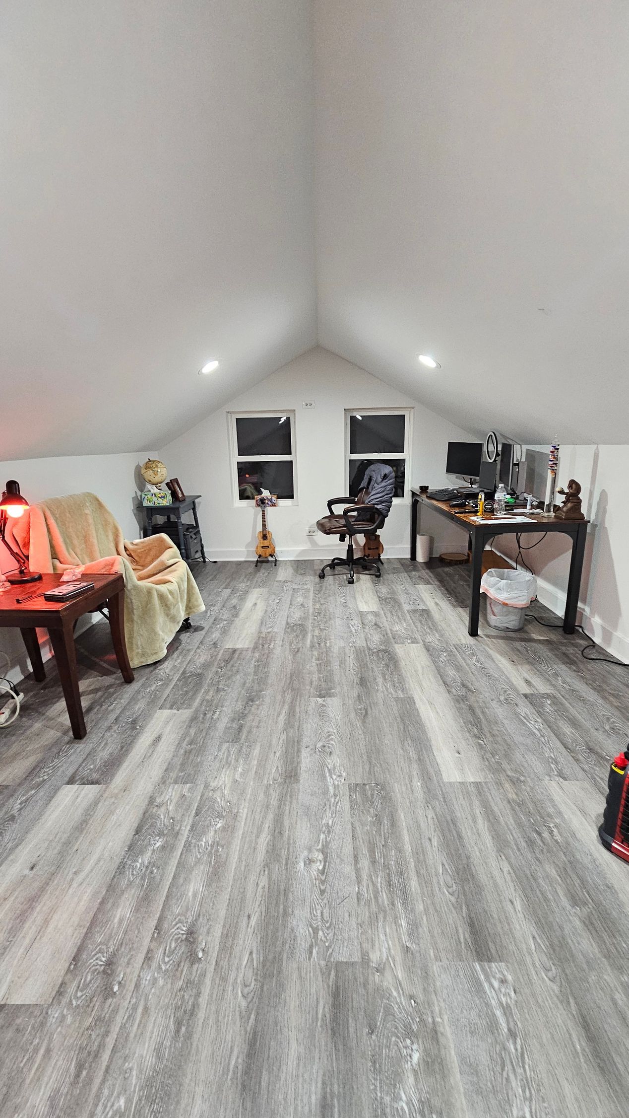A living room with a vaulted ceiling and a desk and chairs.